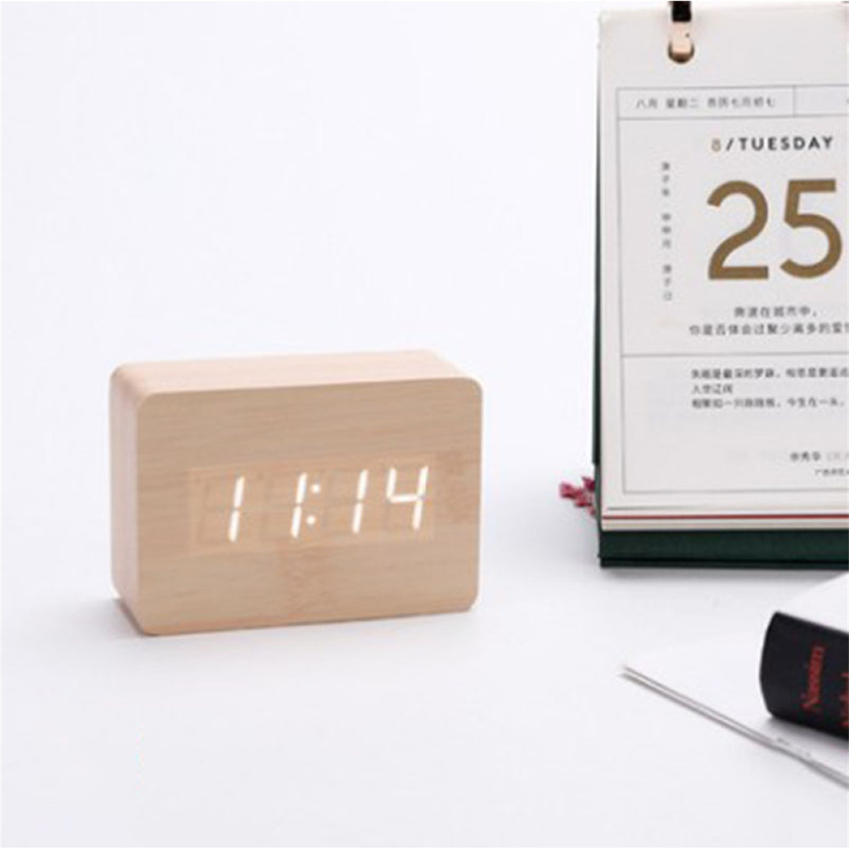 Holzuhr mit Digitalanzeige 11:14, Kalender und Stift daneben.