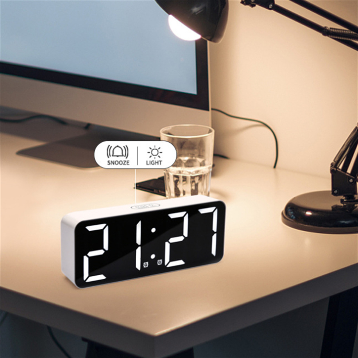 Digitaluhr zeigt 21:27. Schreibtischlampe, Glas und Computer im Hintergrund sichtbar.