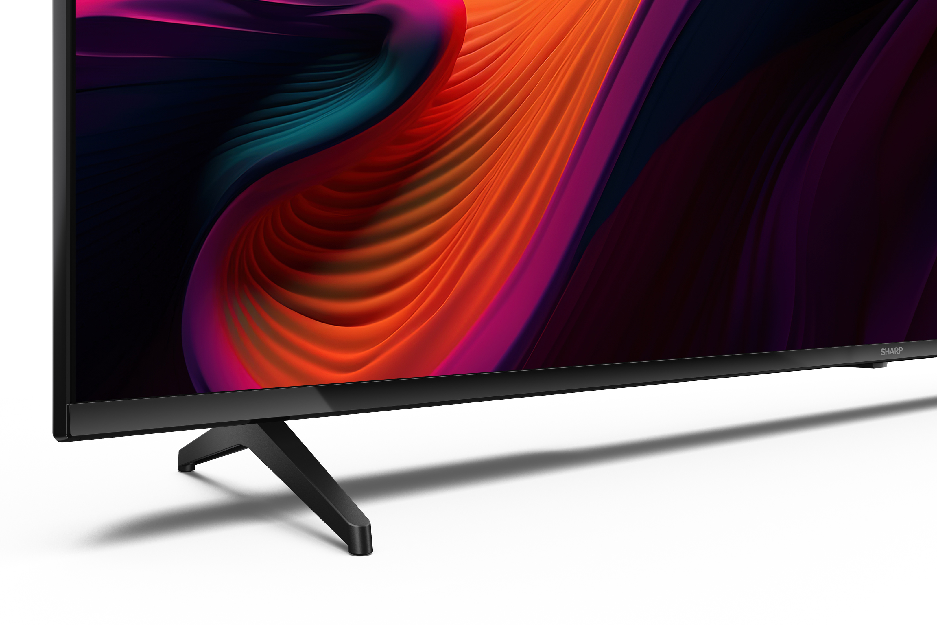 Una TV nera con display astratto colorato, gambe nere e il logo Sharp.