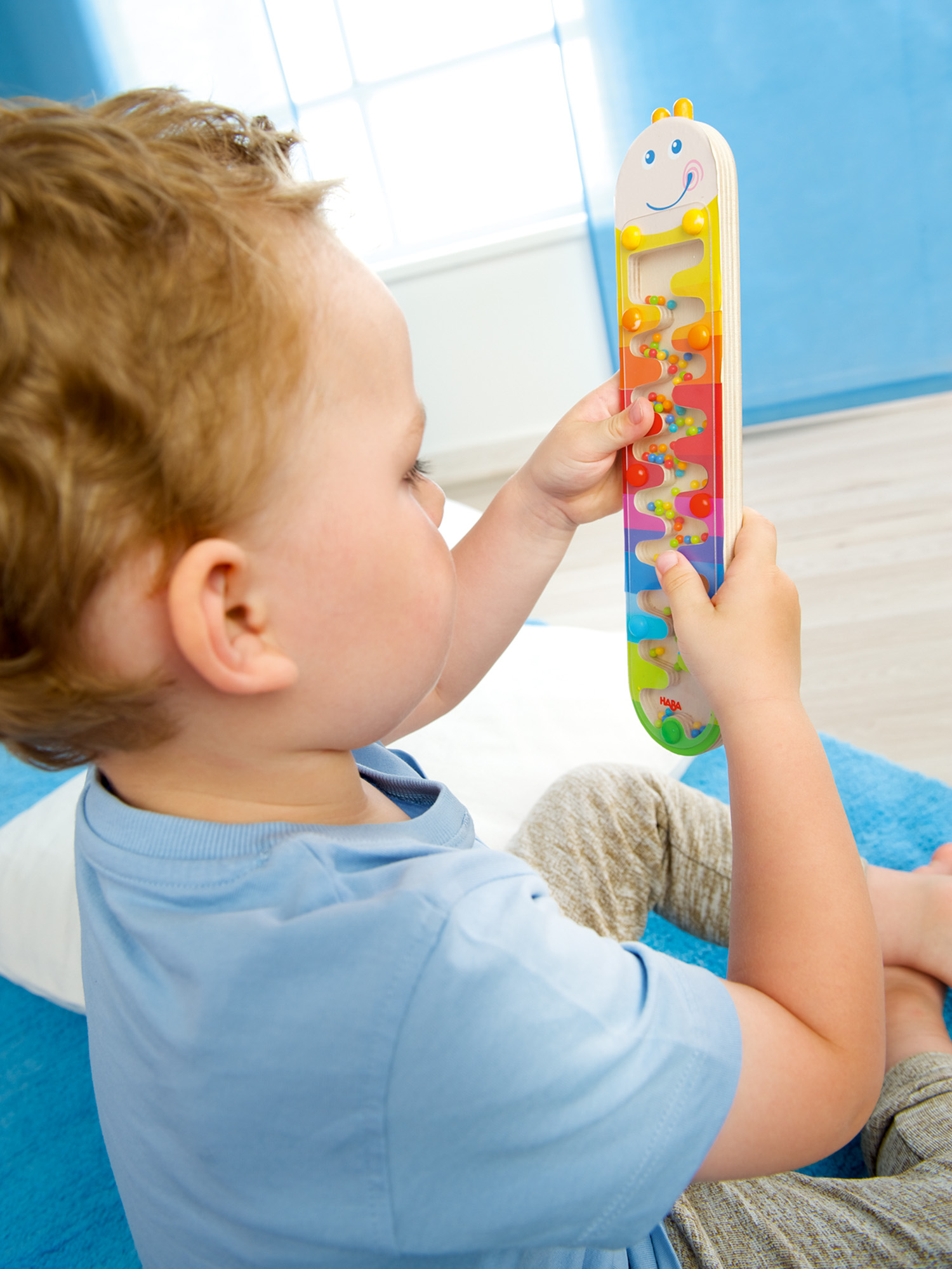 Ein kleines Kind spielt mit einem bunten Holzspielzeug mit Kugeln.