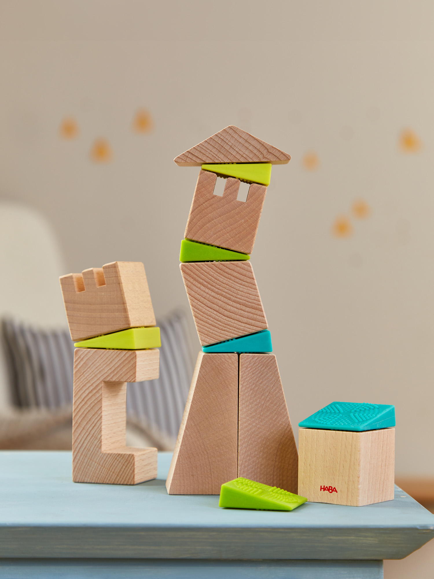 Holzbausteine, angeordnet als Turm und Burg, mit hellblauem Tisch und unscharfem Hintergrund.