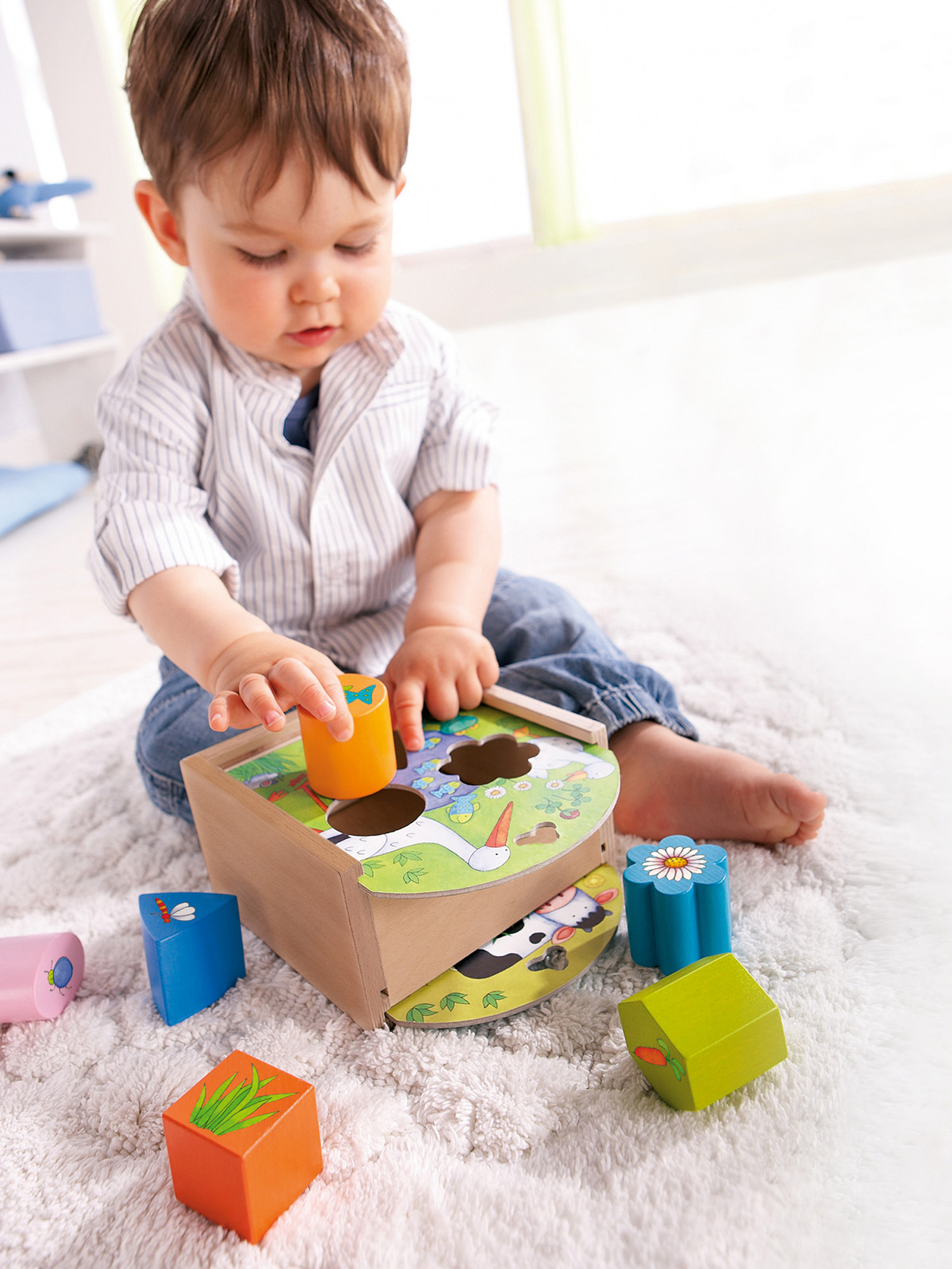 Kleinkind spielt mit einem Holz-Formensortierspielzeug.