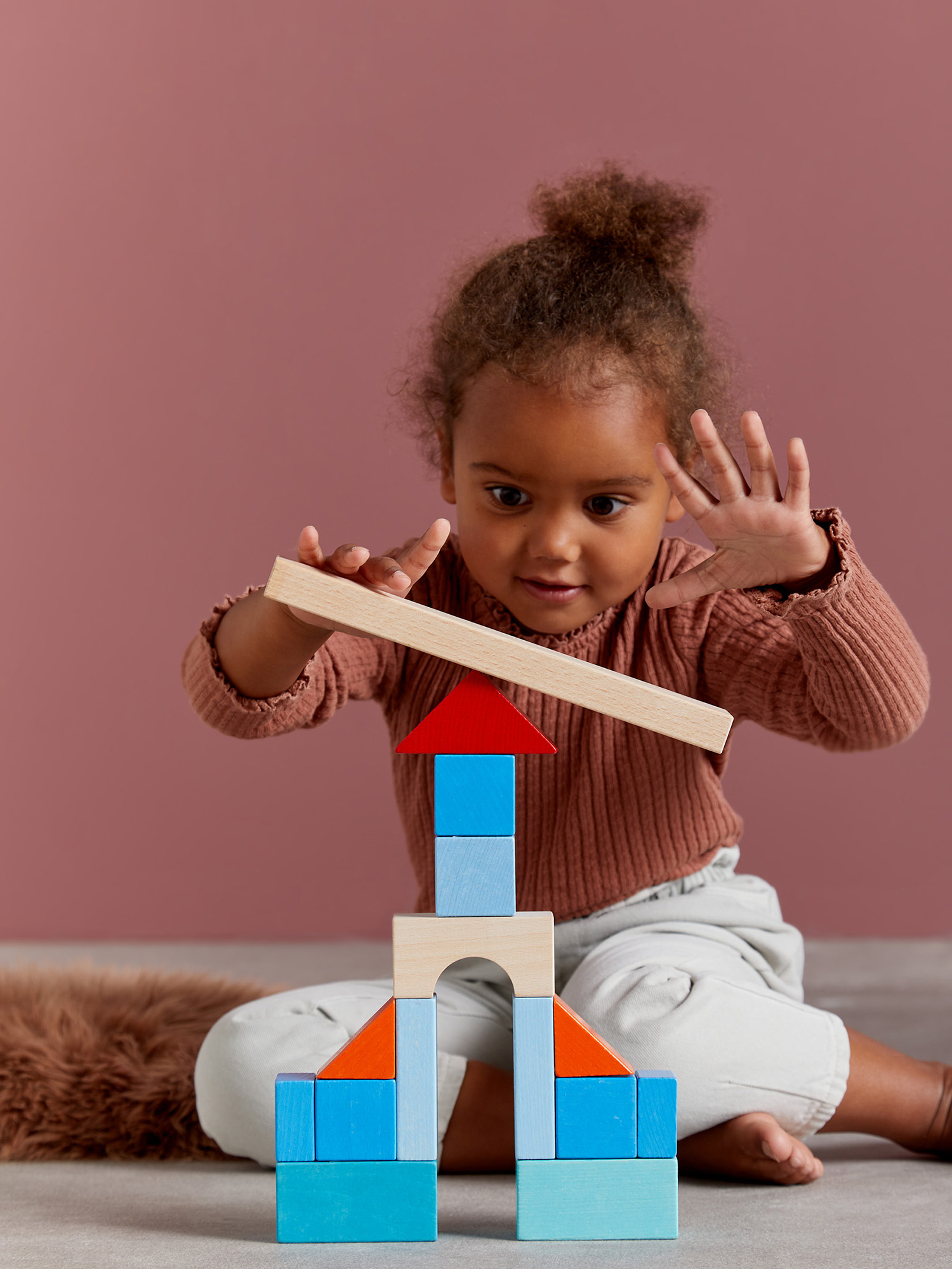 Un bambino sta costruendo con blocchi di legno. Una struttura di blocchi è parzialmente costruita.