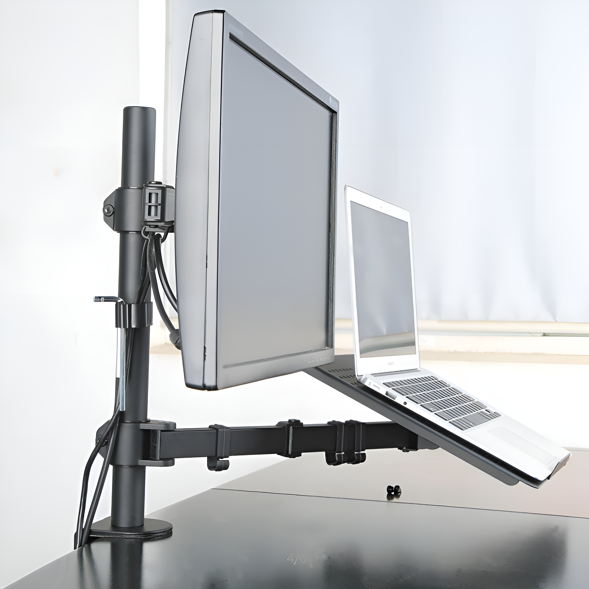Ein Monitor und ein Laptop auf einem Arm montiert. Der Monitor und der Laptop stehen auf einem schwarzen Schreibtisch.