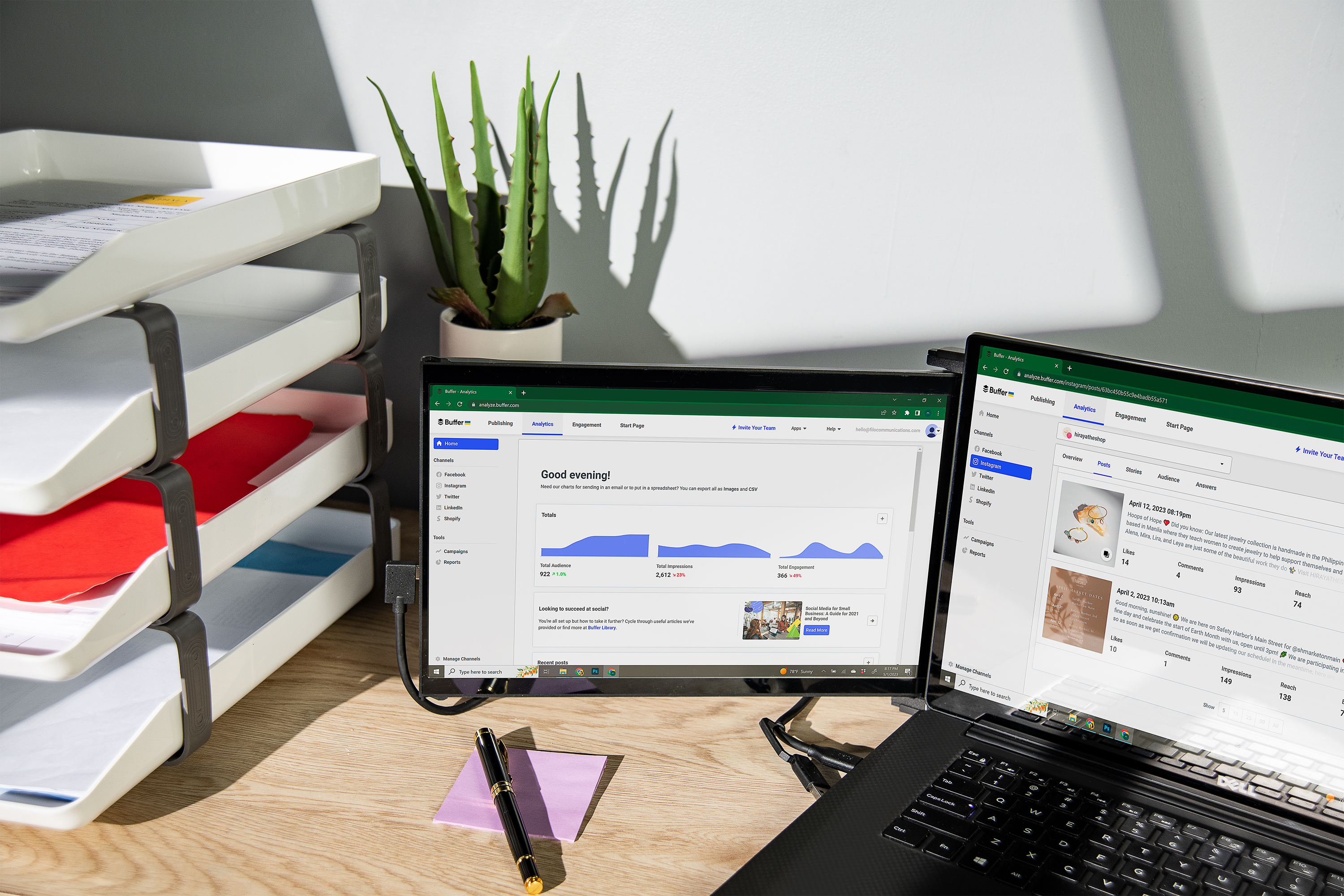 Konfiguracja biurka z laptopem i monitorem zewnętrznym. Po lewej stronie papiery i roślina.