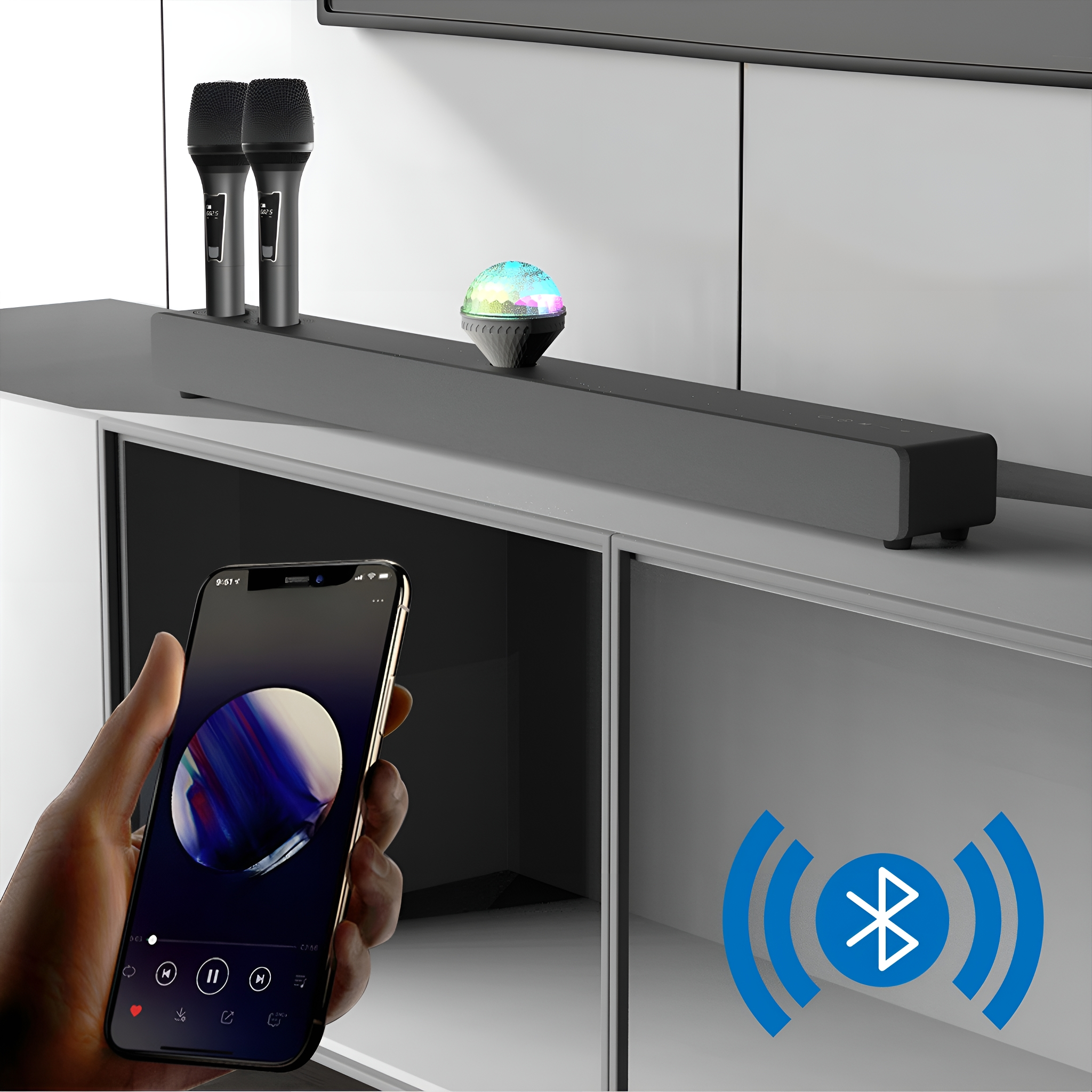 Eine Person, die ein Telefon mit Musik hält, mit einer Soundbar, zwei Mikrofonen und einer Discokugel.