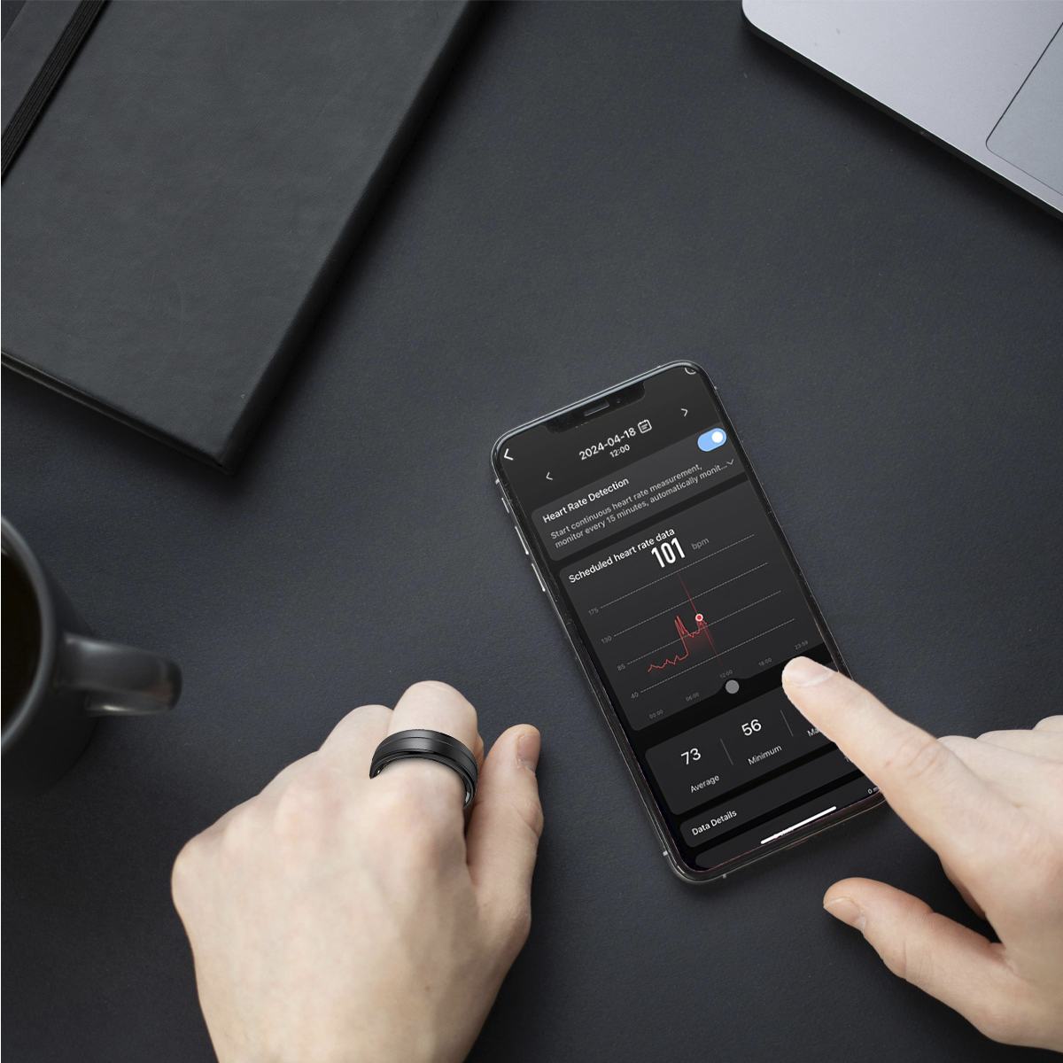 Dłoń z pierścieniem w pobliżu telefonu wyświetlającego dane dotyczące tętna.