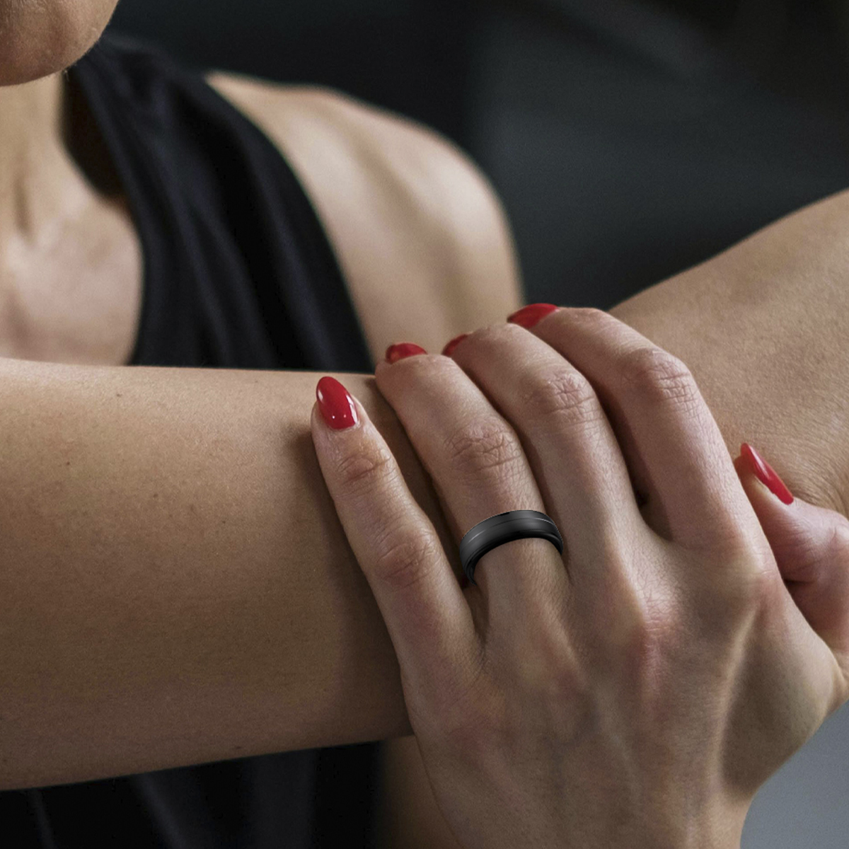 Zbliżenie dłoni kobiety z czarnym pierścieniem na palcu.