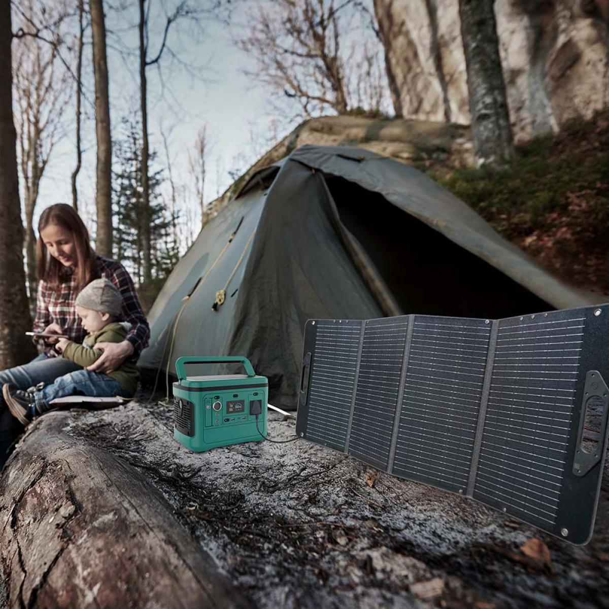 Una donna e un bambino siedono vicino a una tenda in una foresta. Una stazione di alimentazione e un pannello solare sono nelle vicinanze.