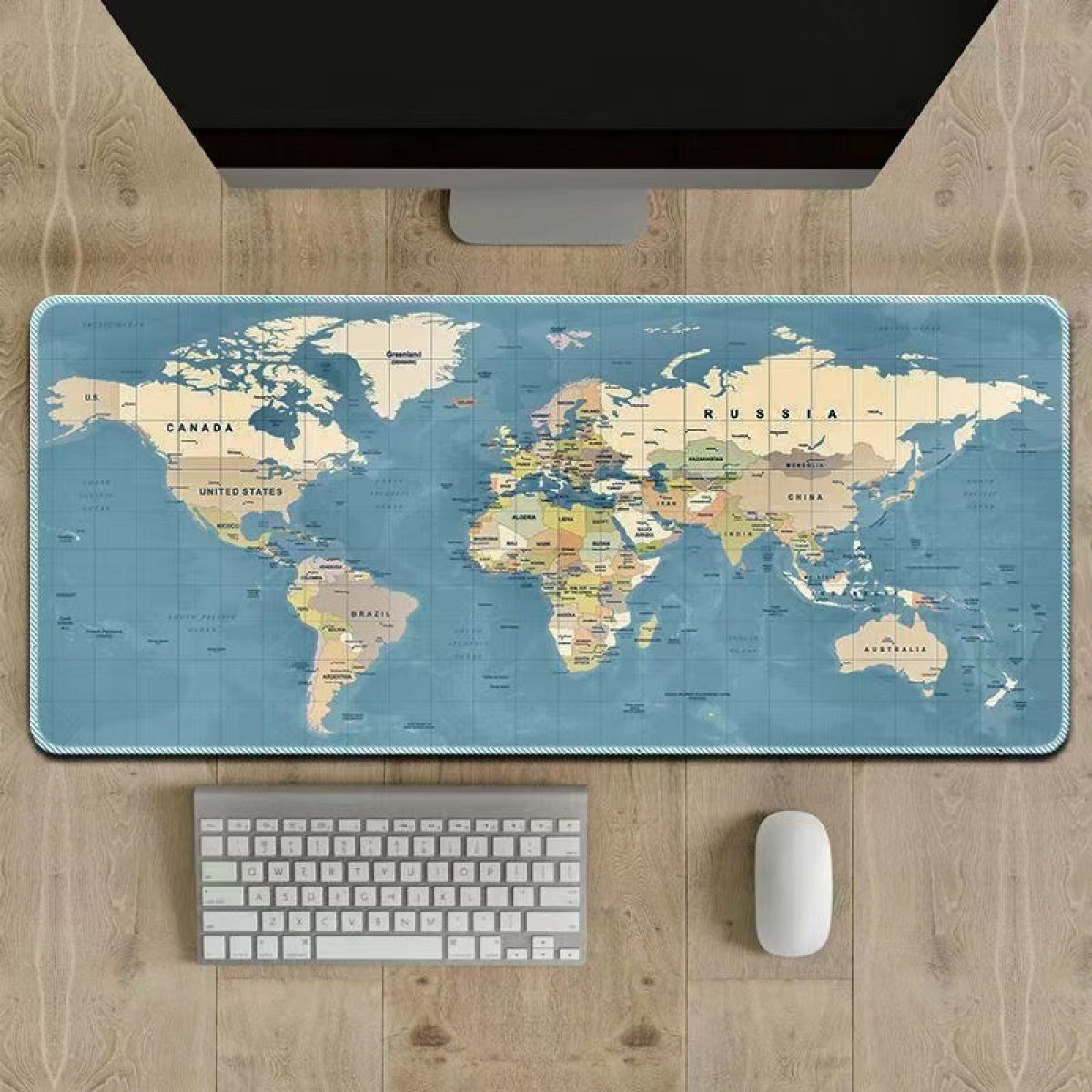 Un tapis de souris avec une carte du monde, un clavier et une souris sur un bureau en bois.