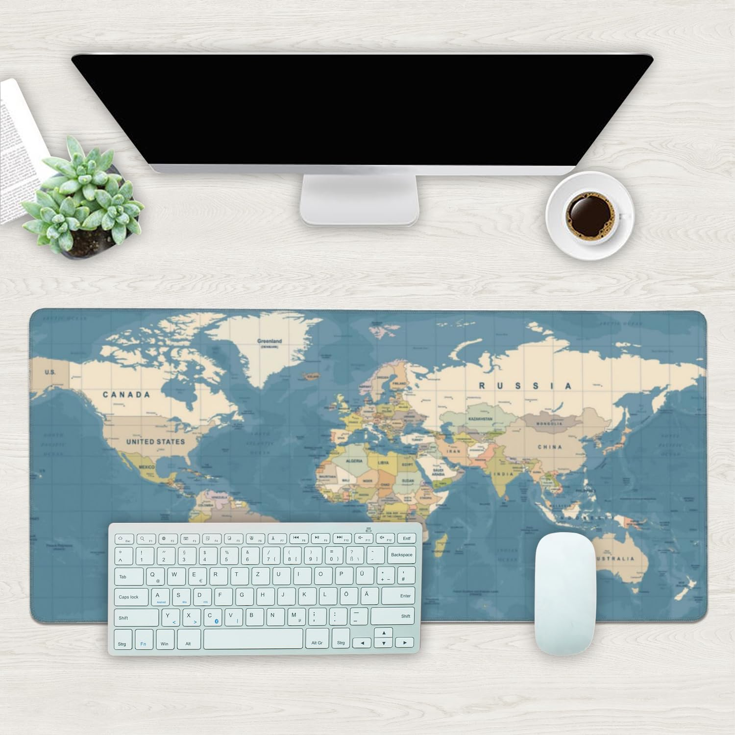Une configuration de bureau avec un tapis de souris carte du monde, clavier, souris et moniteur.