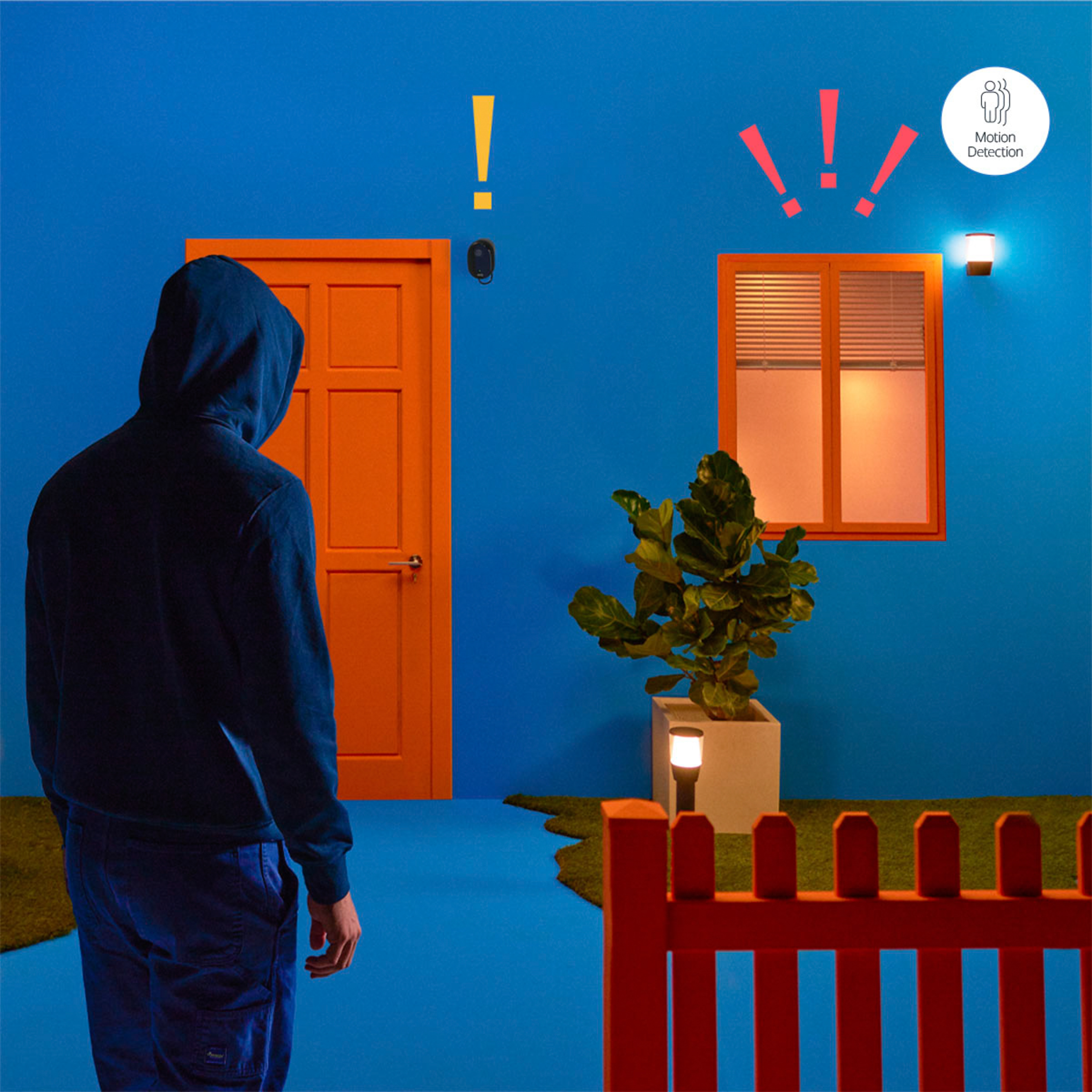 A person in a hoodie stands before a blue house. Orange door and window, red fence.