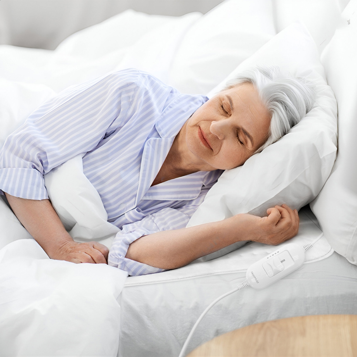 Elderly woman sleeping in bed with a heating pad control cable.