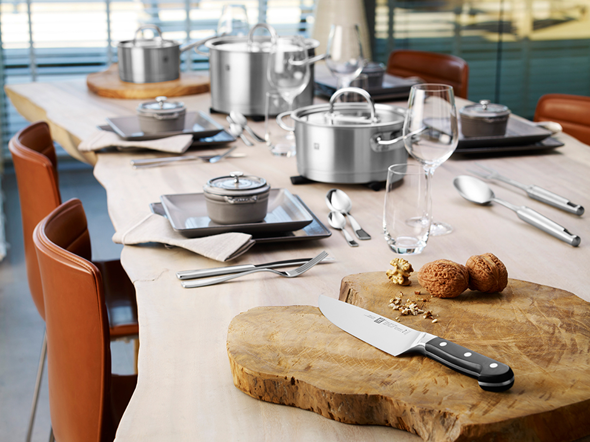 Stół z garnkami, szklankami i sztućcami. Stół jest drewniany i w kuchni.