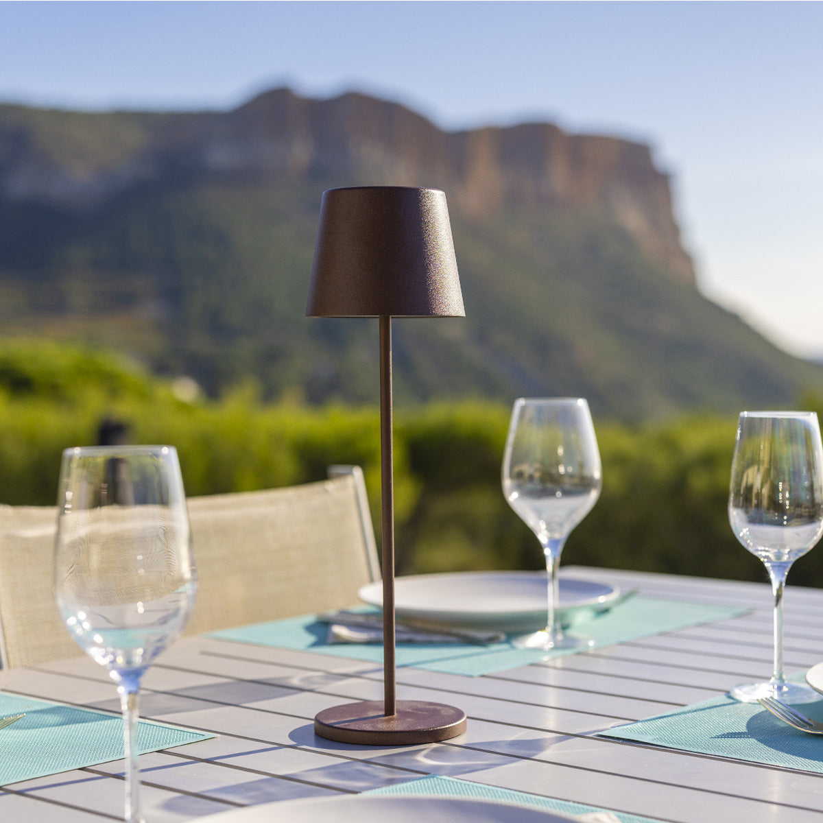 Ein Tisch mit Lampe, Weingläsern und Bergblick.
