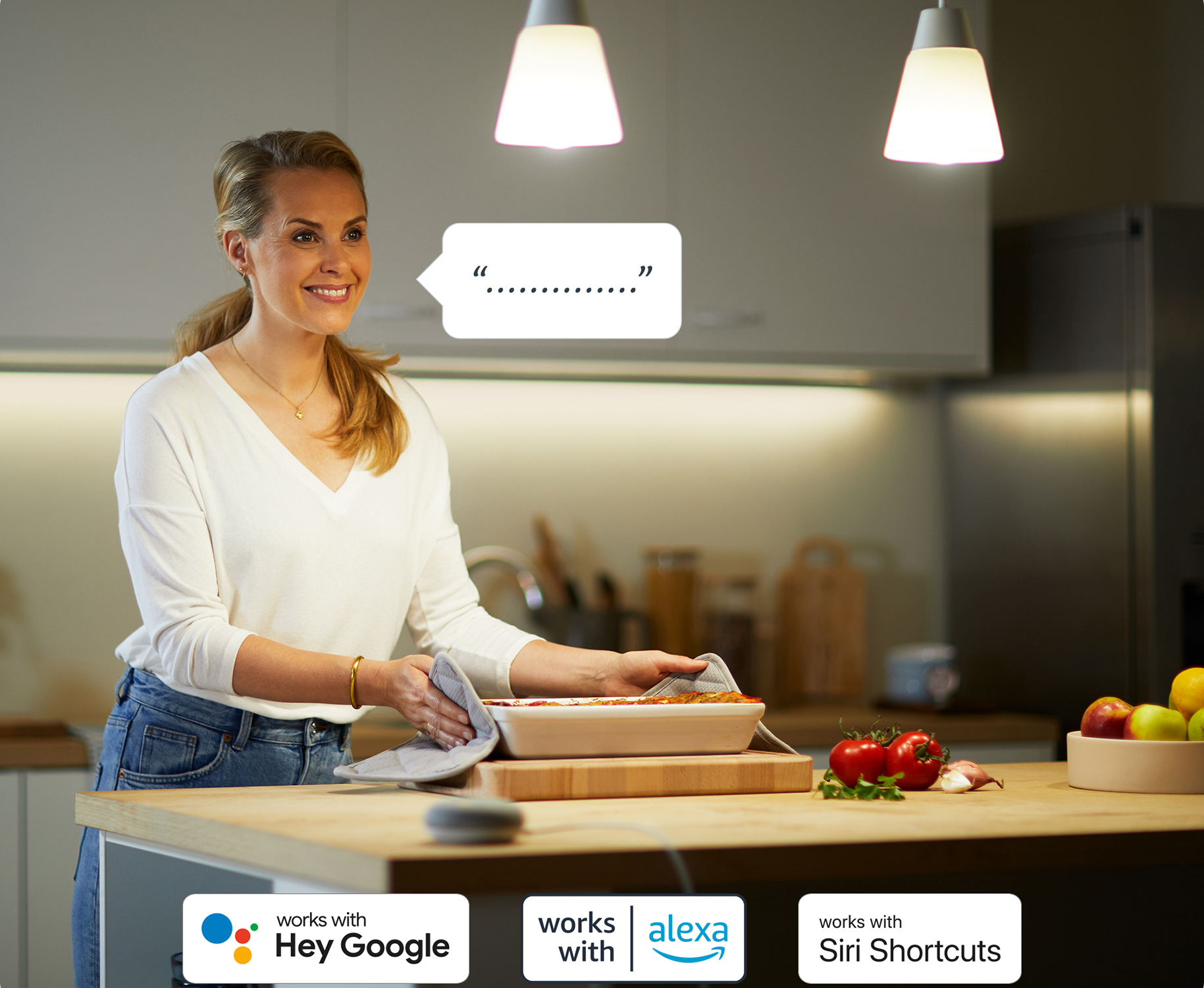 Una donna in cucina con illuminazione intelligente, forno con cibo e loghi assistente vocale.
