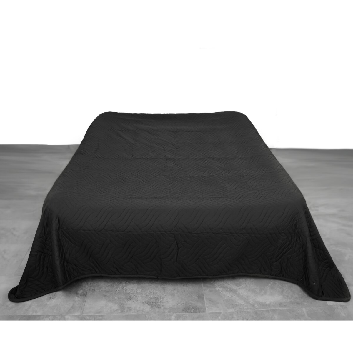Schwarze, gesteppte Tagesdecke auf einem grau gefliesten Boden. Die Tagesdecke bedeckt das Bett.