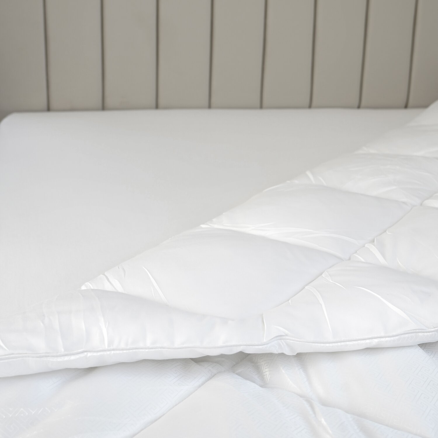 Ein weißes Bett mit einer teilweise bedeckenden Bettdecke. Das Muster des Bettlakens ist sichtbar.