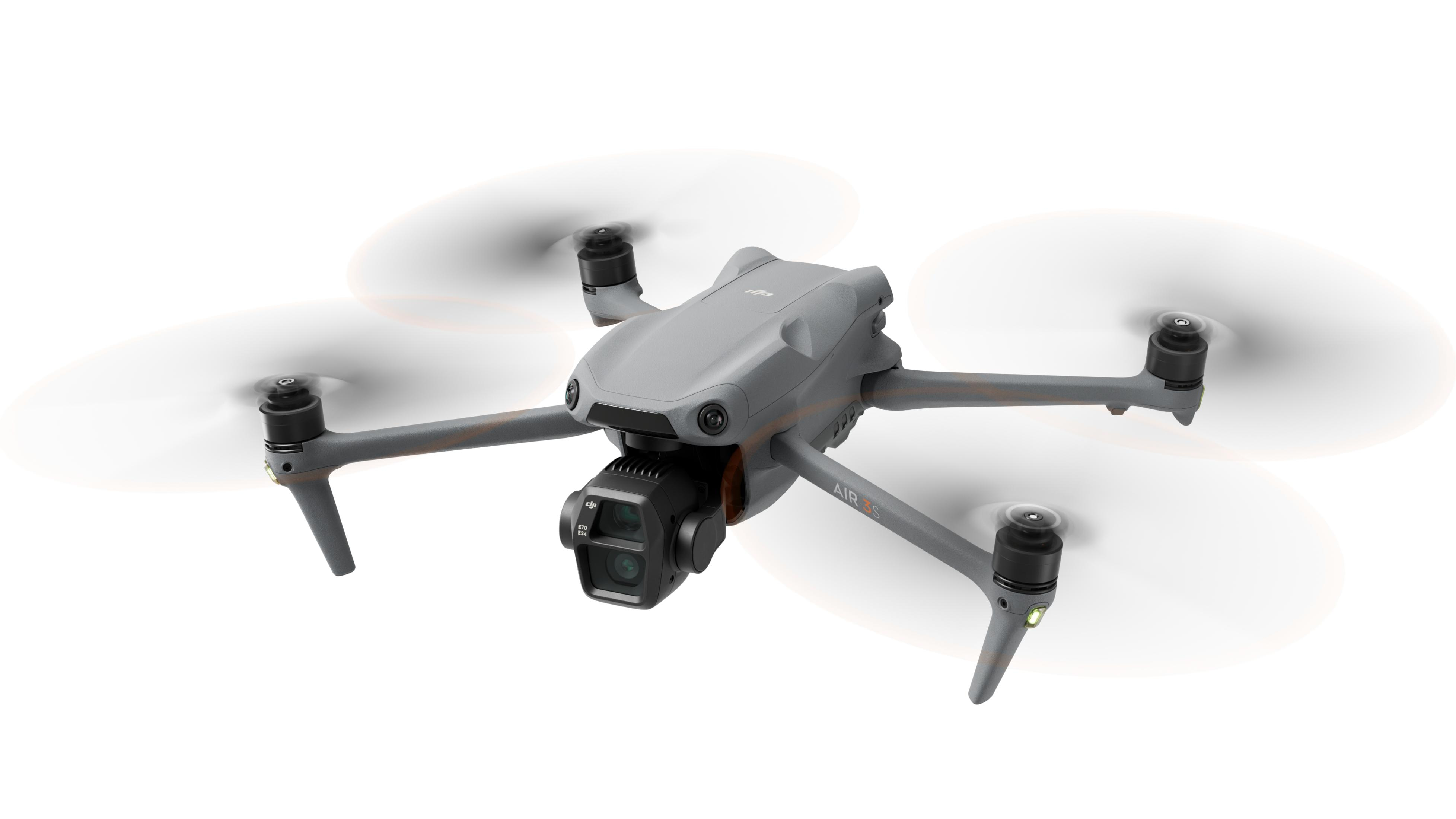 Drone grigio a mezz'aria, eliche in rotazione, su sfondo bianco.
