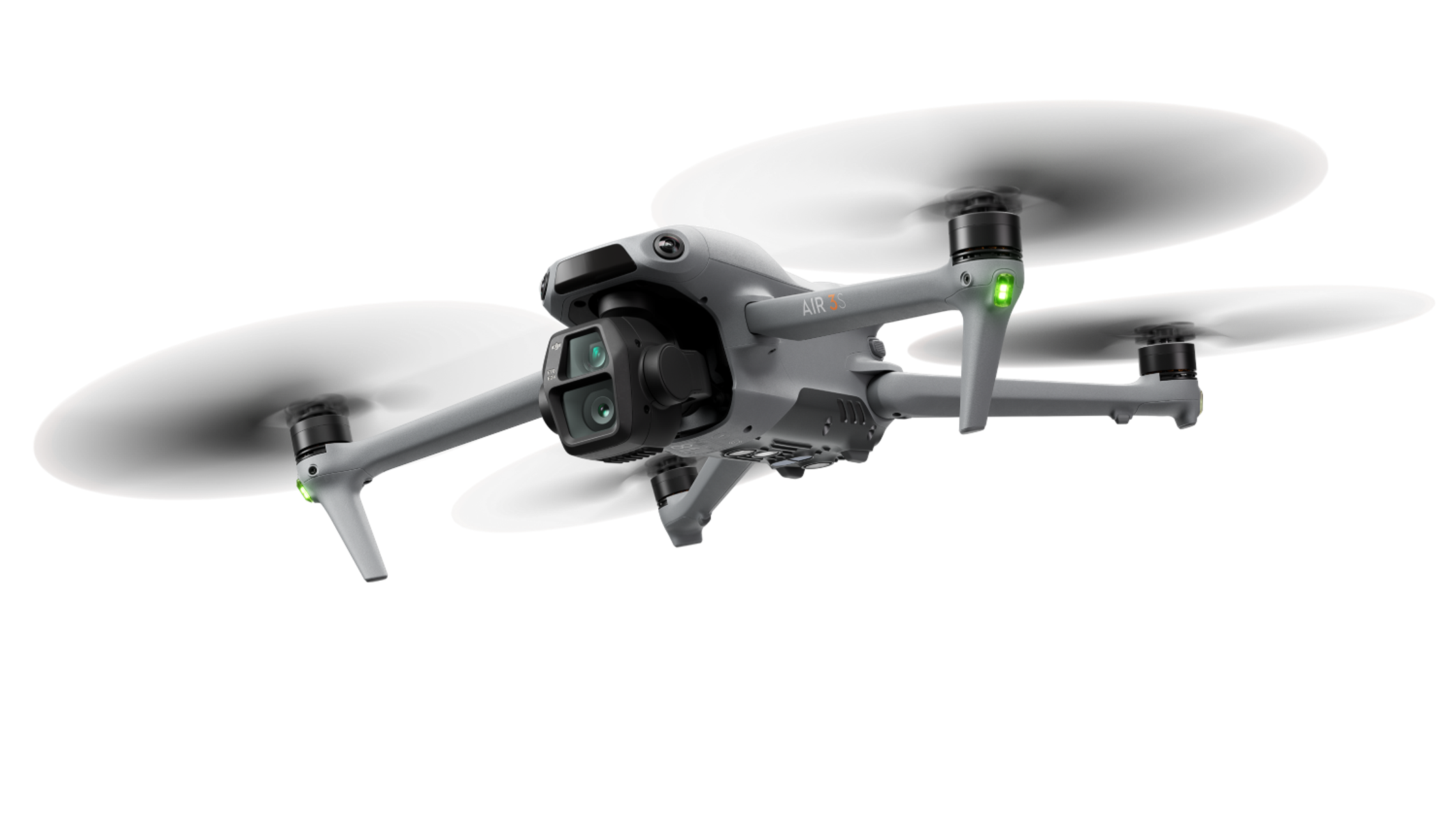 Un drone grigio con quattro eliche, fotocamera e carrello di atterraggio, su sfondo nero.