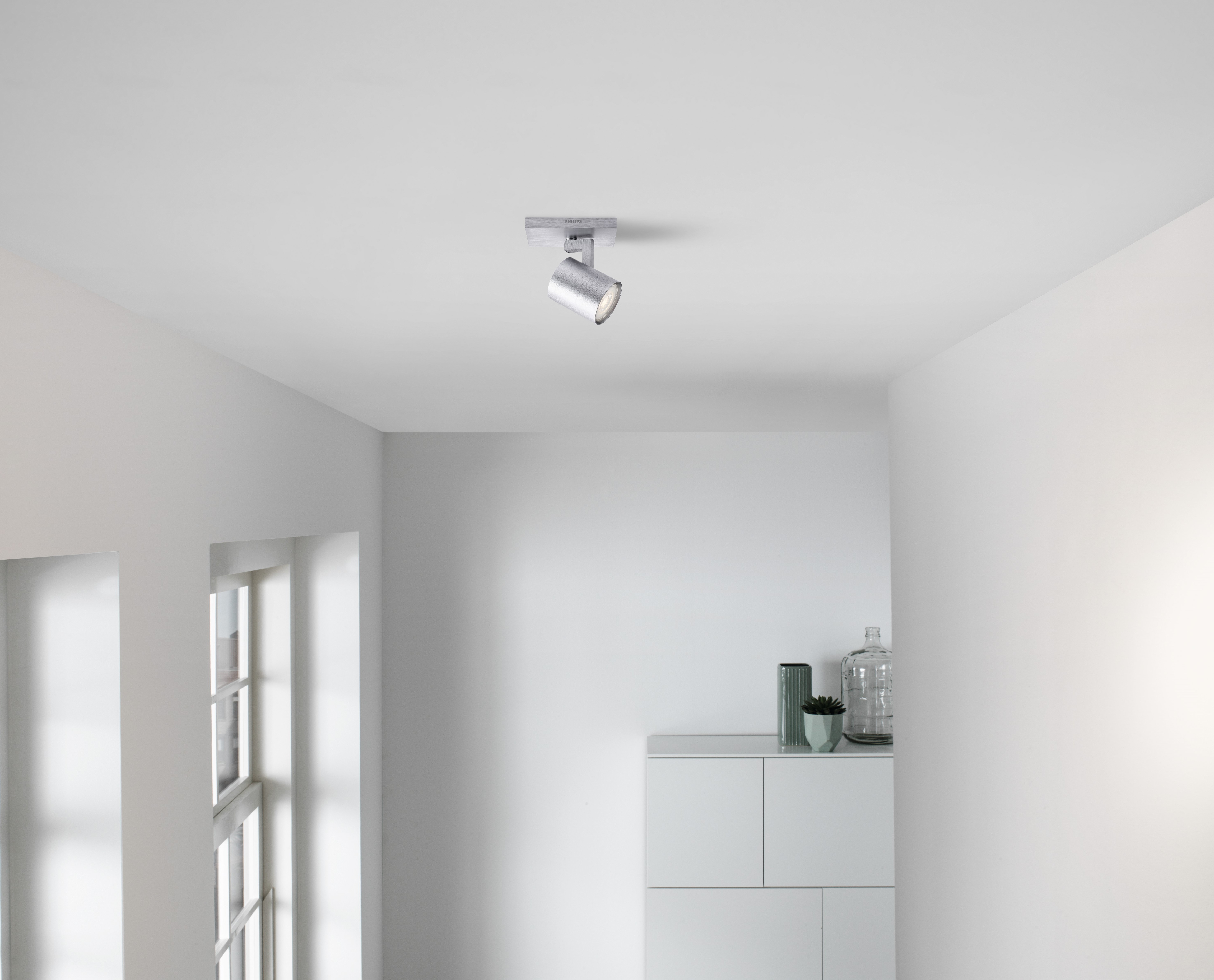 Ceiling with a spotlight. White walls, room with a cabinet and a window.