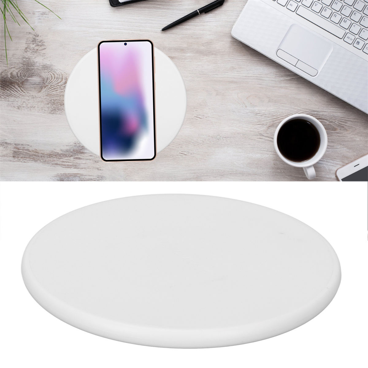 Ein weißes kabelloses Ladegerät mit einem Telefon darauf sowie eine Kaffeetasse, ein Laptop und ein Stift.