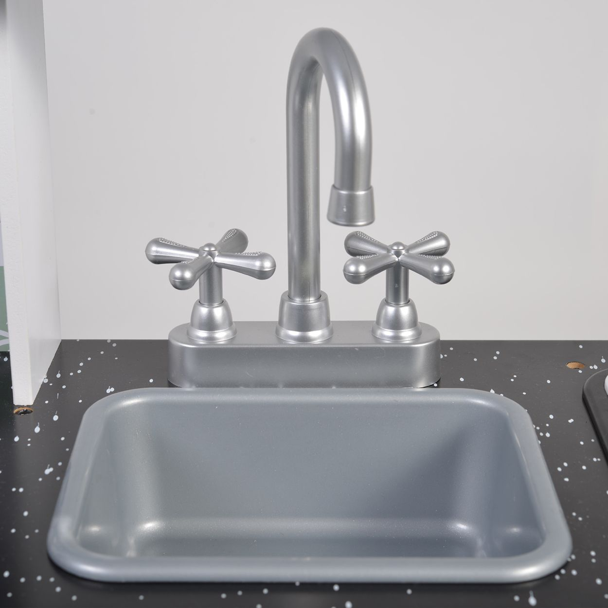 Ein Spielzeug-Küchenspüle mit einem verchromten Wasserhahn und einem grauen Spülbecken.