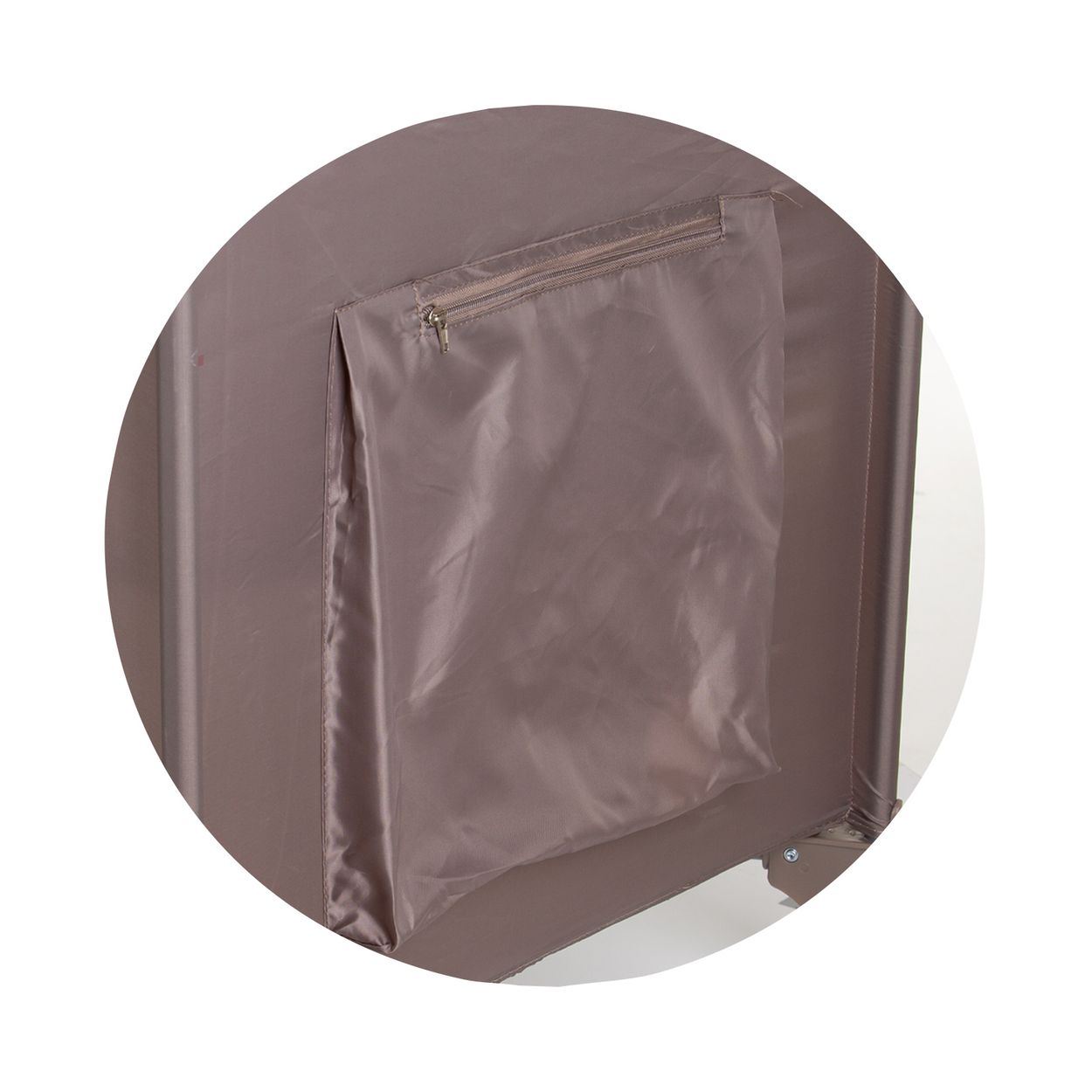 Primer plano de un bolsillo marrón en el lateral de una cuna de viaje. Bolsillo con cremallera sobre fondo marrón claro.