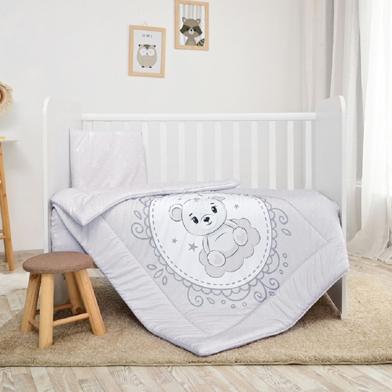 Ein Babybett mit Bettwäsche, einem kleinen Hocker und Wandkunst, weißer Hintergrund.