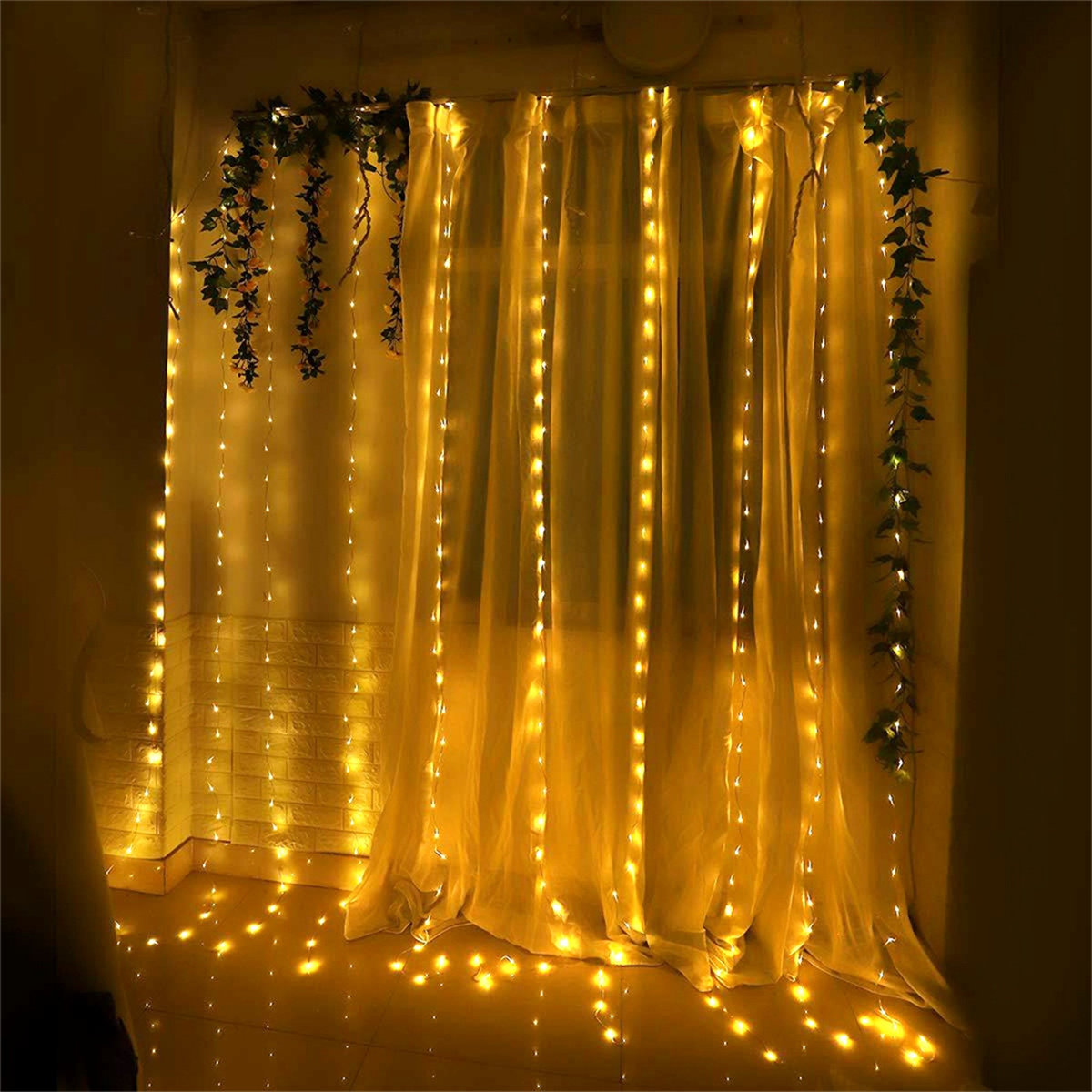 Vorhänge, beleuchtet mit Lichterketten und Grünpflanzen am Fensterrahmen.