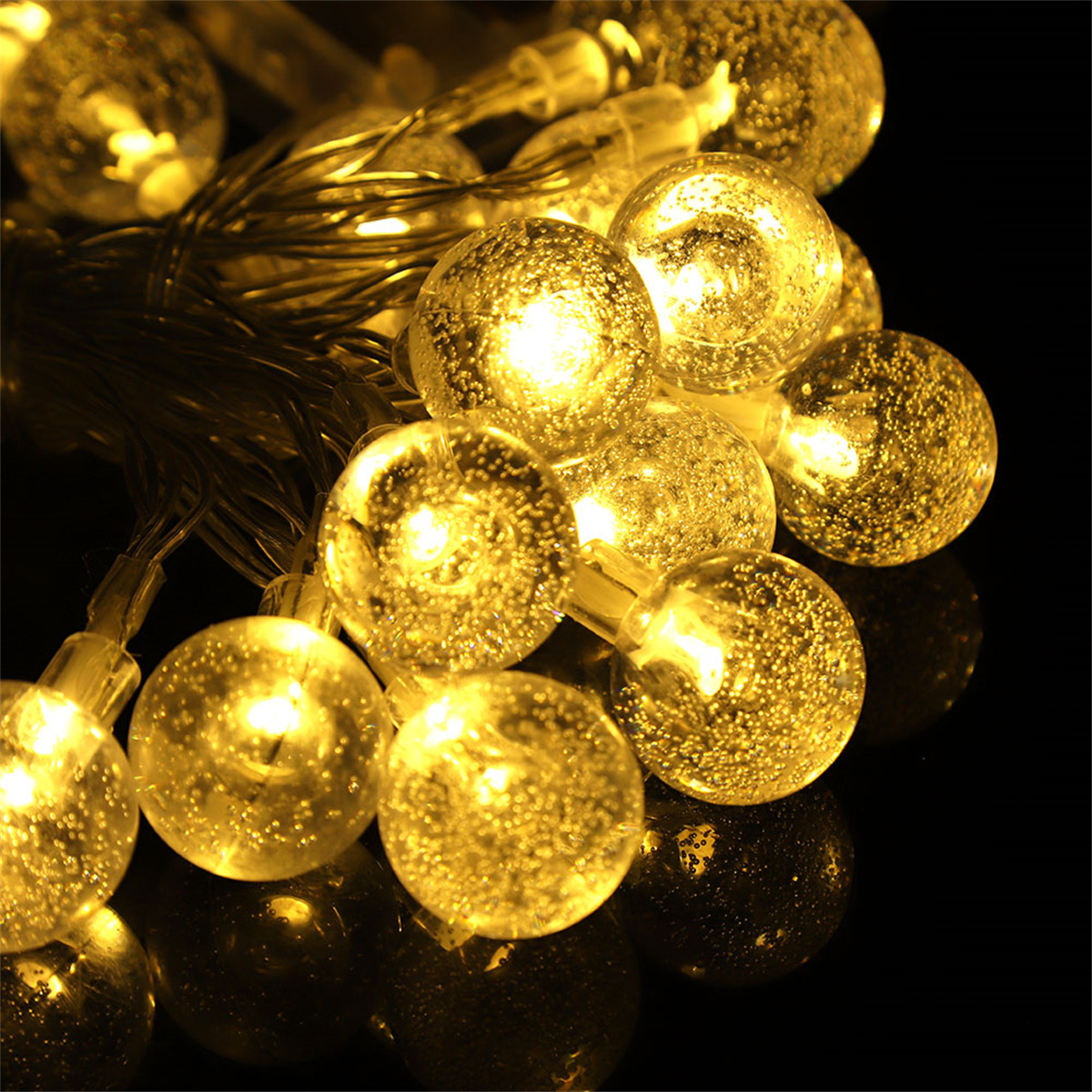 Schnur aus gelben LED-Leuchten. Sie sind kugelförmig und leuchten hell auf einer dunklen Oberfläche.