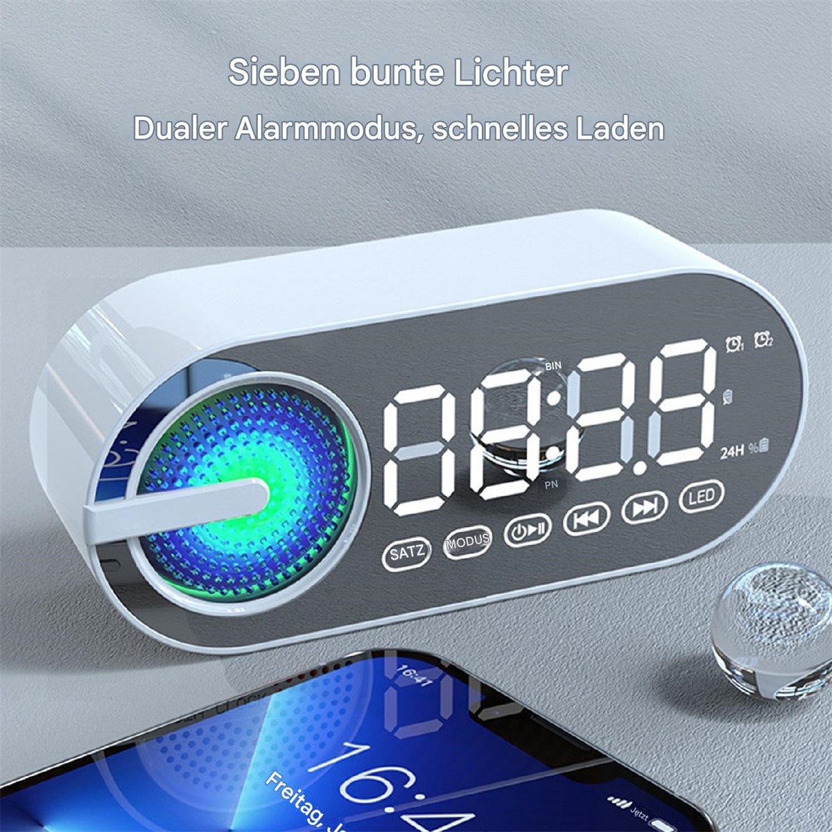 Weiß-grauer digitaler Wecker mit farbenfroher LED-Anzeige, Telefon im Vordergrund.