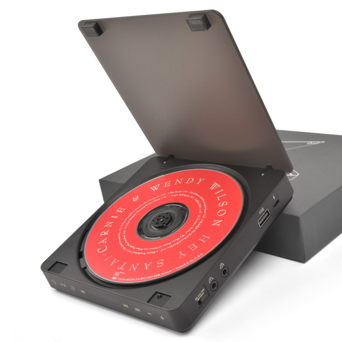 Schwarzer tragbarer CD-Player mit einer CD darin. Der Deckel ist geöffnet. Im Hintergrund befindet sich eine Box.
