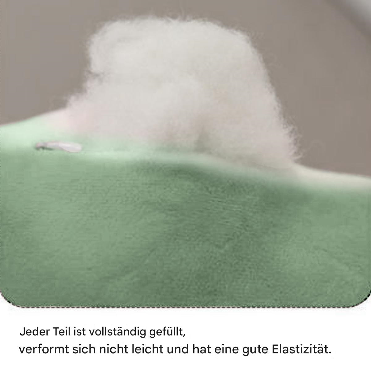 Nahaufnahme eines weichen, grünen Kissens. Weiße, flauschige Füllung kommt heraus.