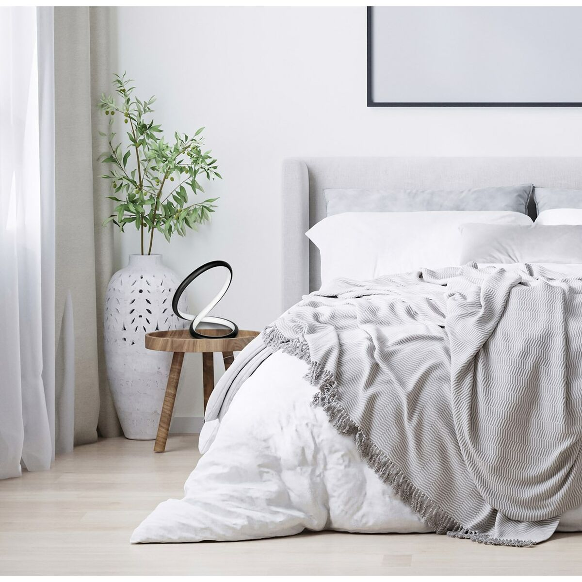 Una escena de dormitorio con una cama, una manta, una lámpara y un jarrón con ramas.