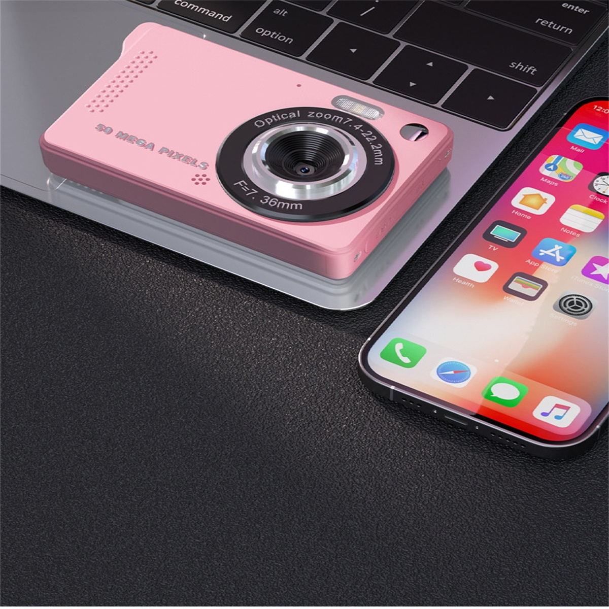 Eine rosa Digitalkamera und ein Smartphone liegen auf einer Laptop-Tastatur. Die Kamera ist beschriftet.