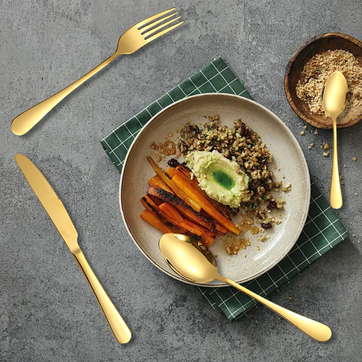 Goldene Utensilien auf einem Teller mit Essen. Karotten, Körner und Grün sind sichtbar.