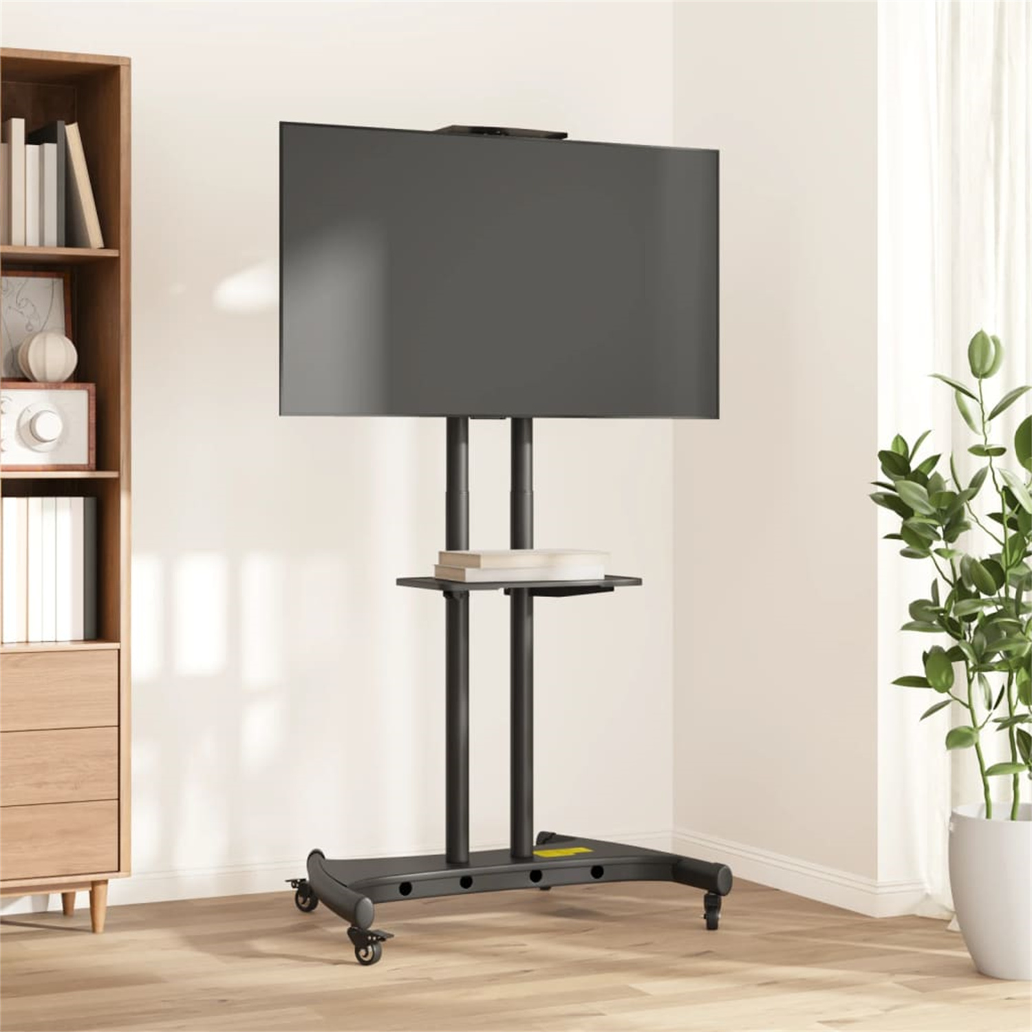 Ein Fernseher auf einem Rollständer. Ein Bücherregal und eine Pflanze sind an den Seiten.