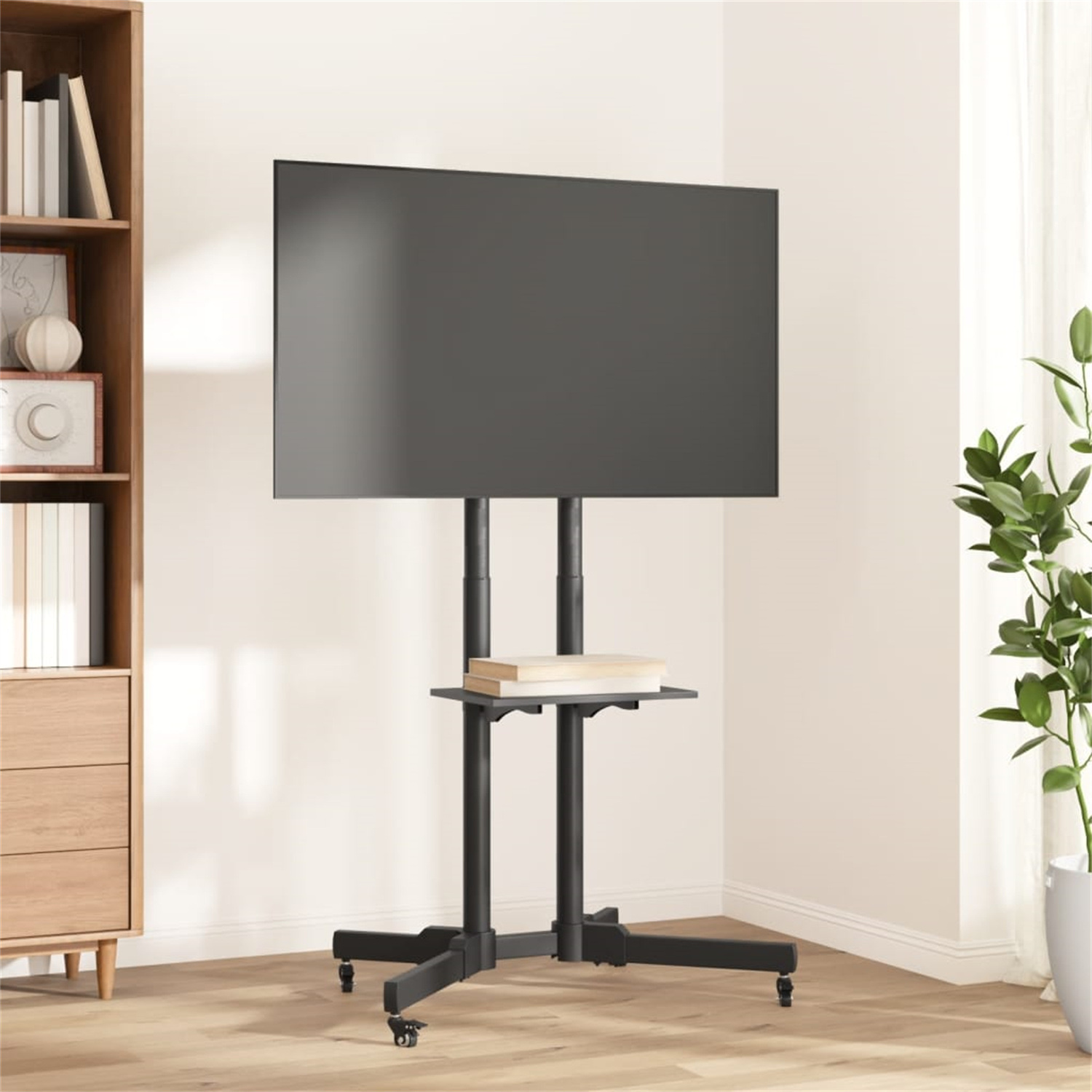 Ein Fernseher auf einem schwarzen Ständer mit Regal. Ein Bücherregal und eine Pflanze sind im Hintergrund.