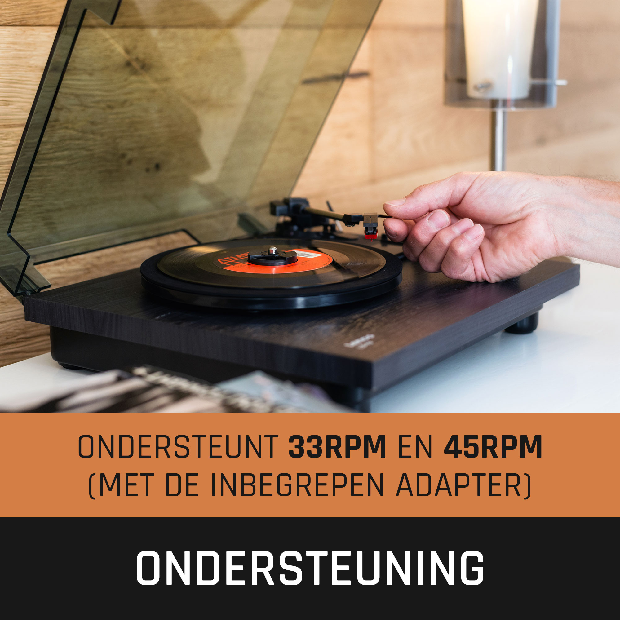 Een hand die een platenspeler instelt met een zwarte vinylplaat.