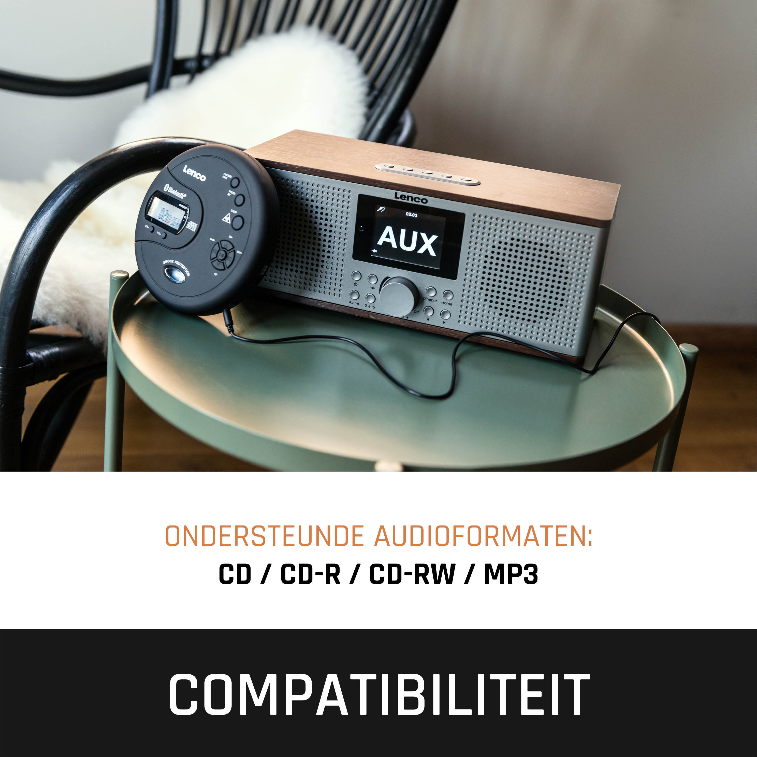Een houten radio met cd-speler op een groene tafel. Een zwarte stoel met wit kussen op de achtergrond.