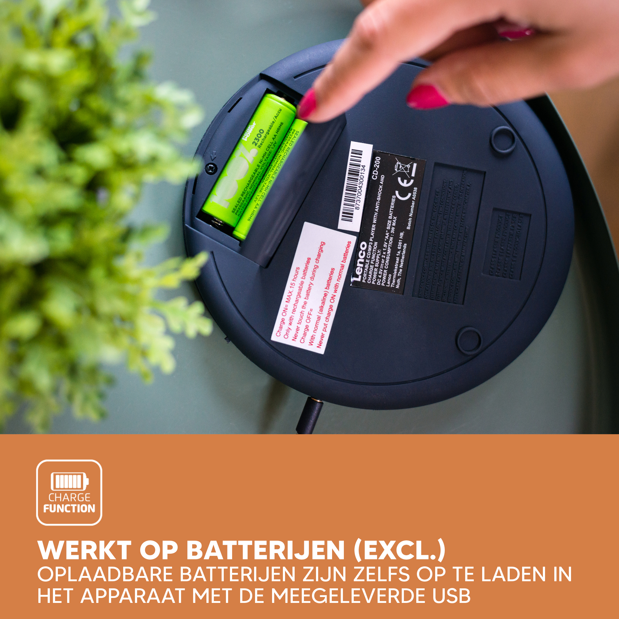 A person's hand inserts a battery into a device. Text and charging symbols are present.