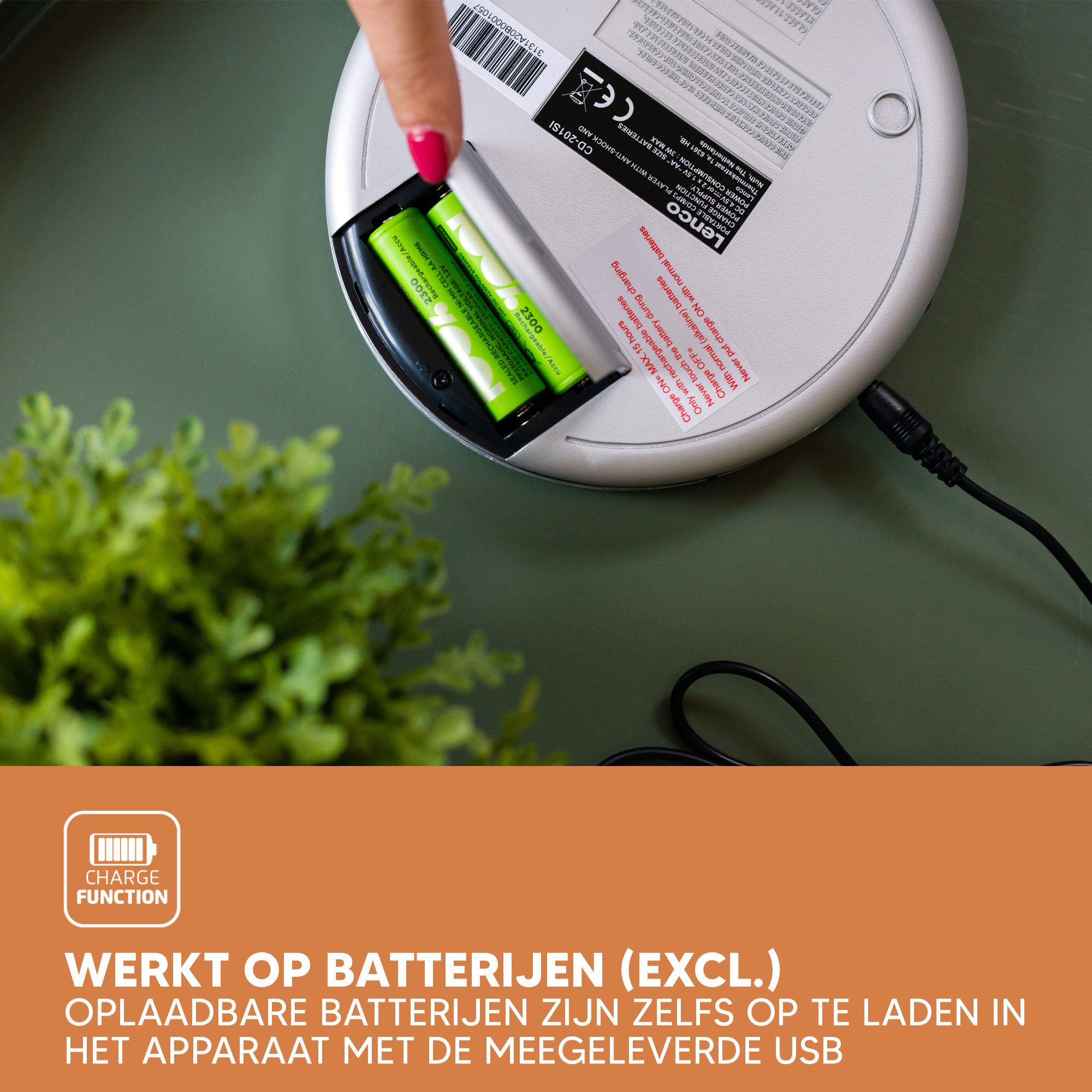 A person charges two green batteries. The batteries are in a white device, with a charging cable plugged in.