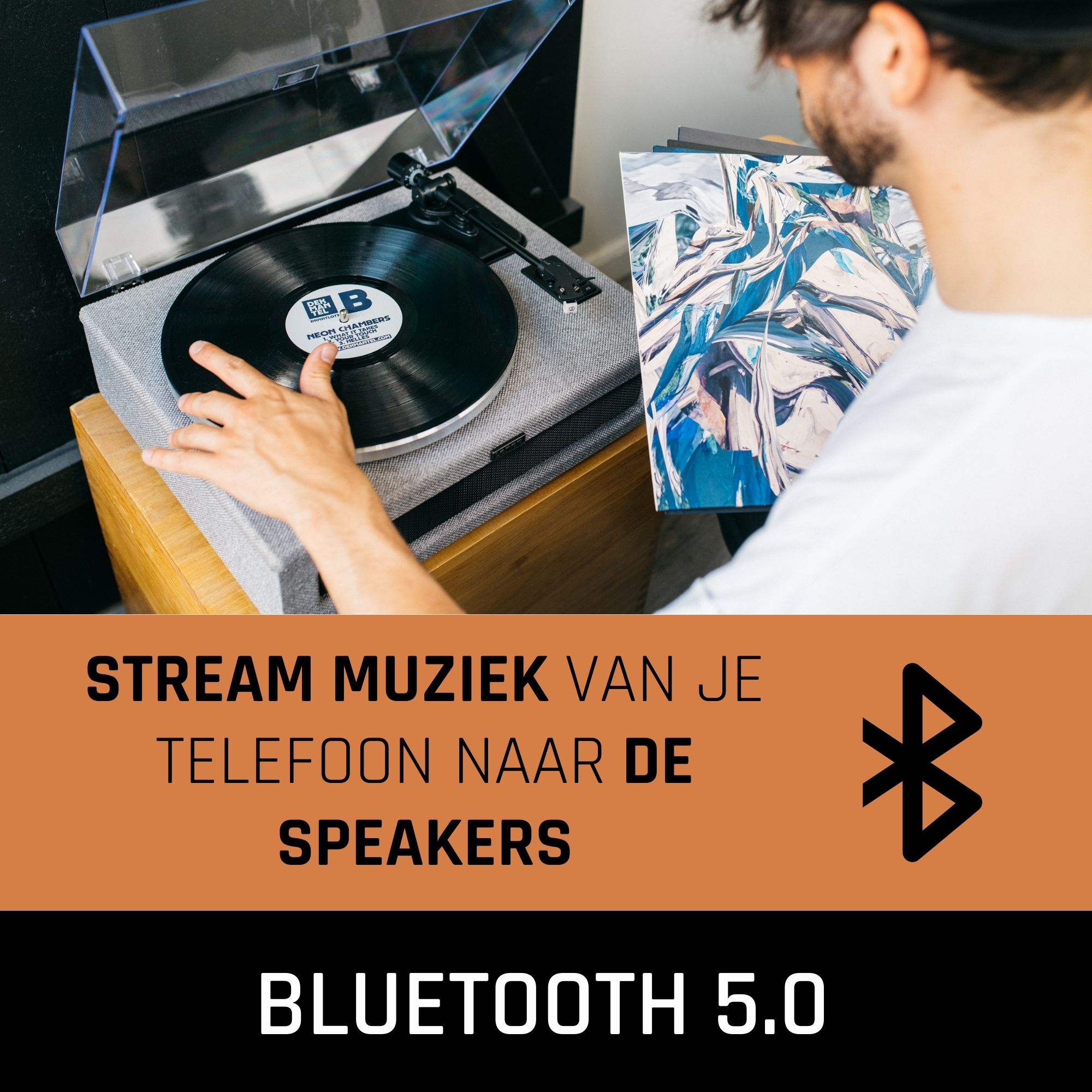 Man met baard houdt een vinylplaat boven een platenspeler. Er is een Bluetooth-pictogram aanwezig.