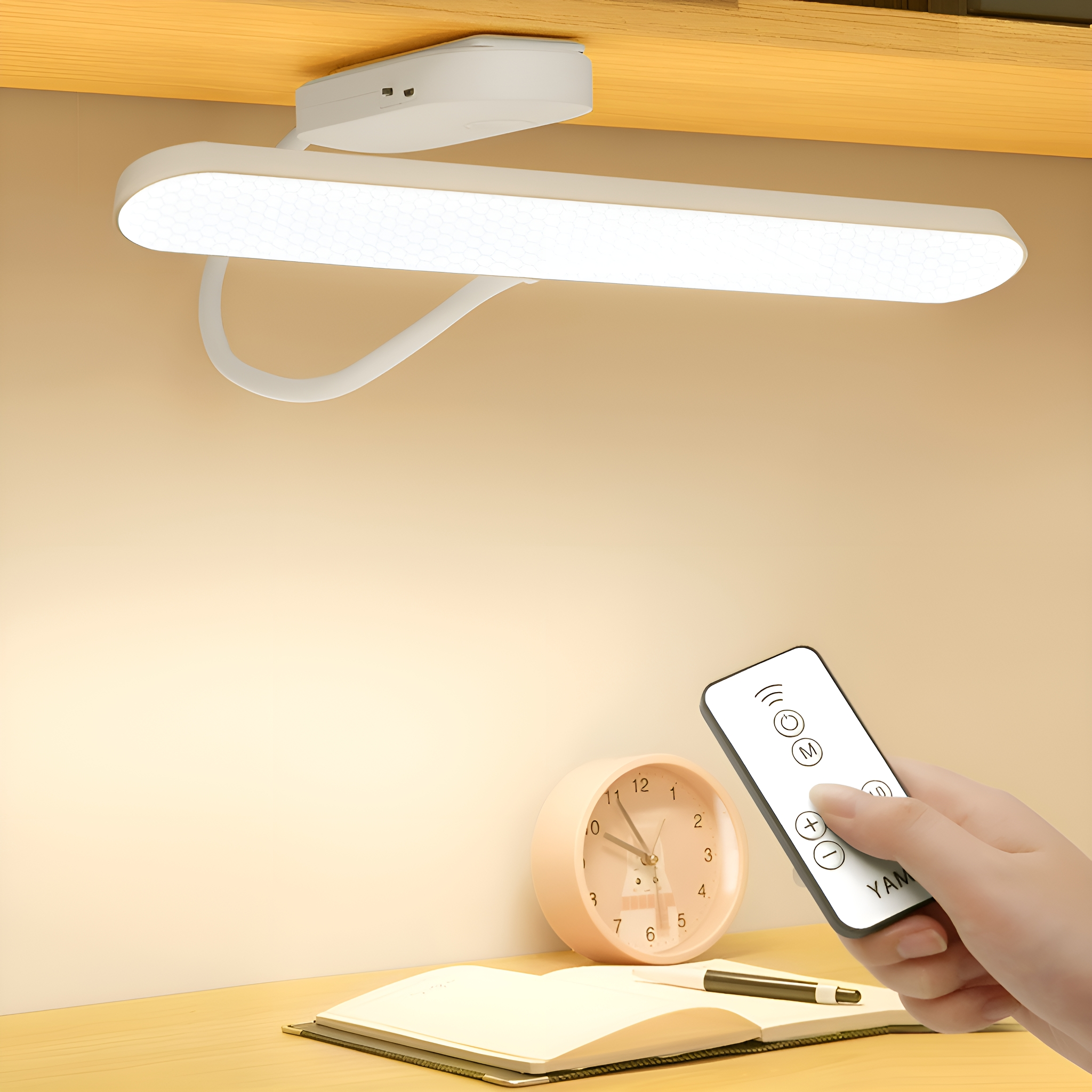 Eine Schreibtischlampe mit Fernbedienung und einer Uhr auf einem Holzschreibtisch, mit hellem Hintergrund.