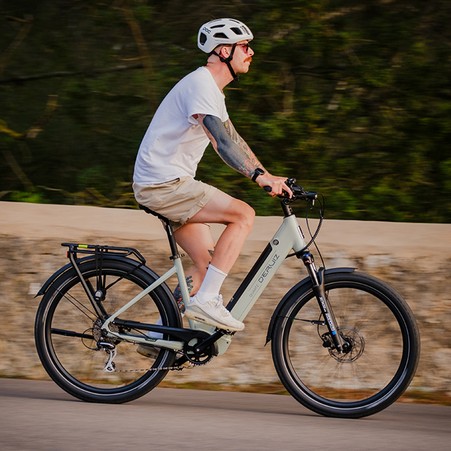 Mann fährt mit einem hellgrünen E-Bike auf einem Weg neben Bäumen.