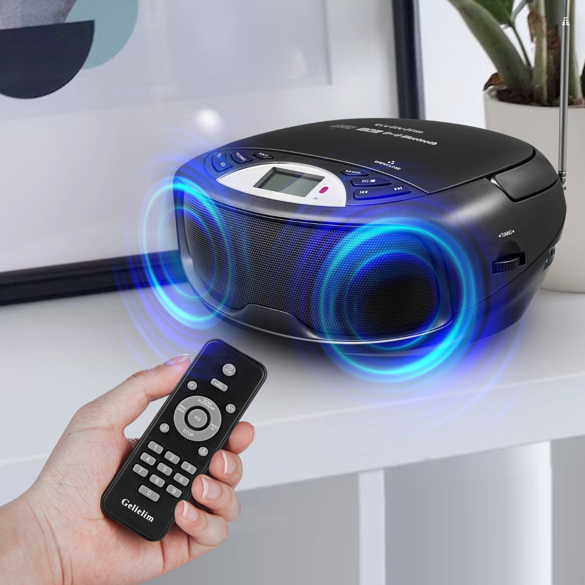 Schwarzer CD-Player mit Fernbedienung, auf weißer Oberfläche mit Pflanze im Hintergrund.