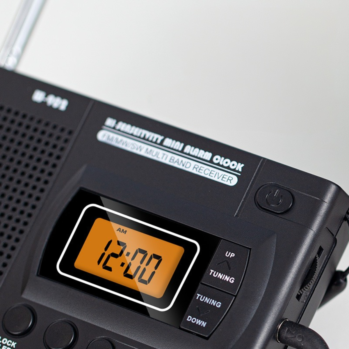 Ein schwarzer Radiowecker mit orangefarbener Digitalanzeige, die die Zeit 12:00 anzeigt.