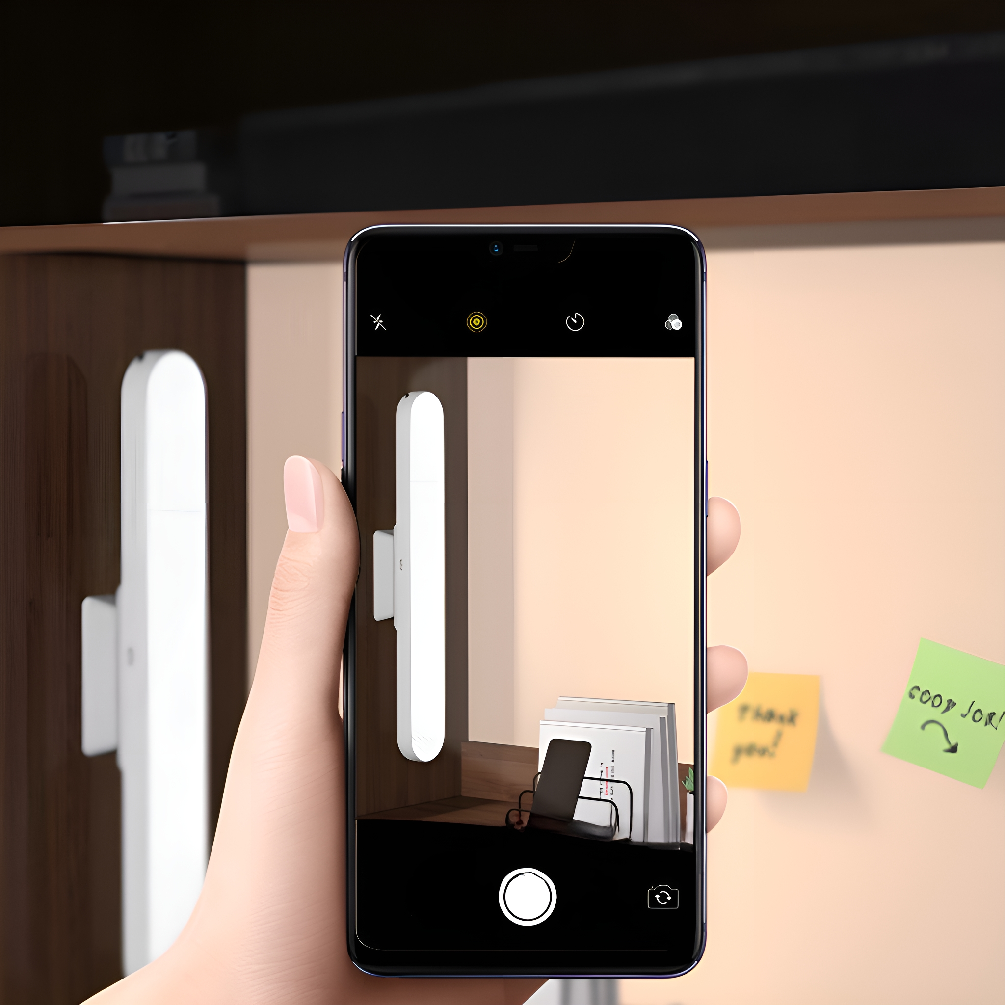 Hand hält Telefon, das ein Foto von einer Wand mit Licht und Haftnotizen macht. Telefonbildschirm zeigt Foto.