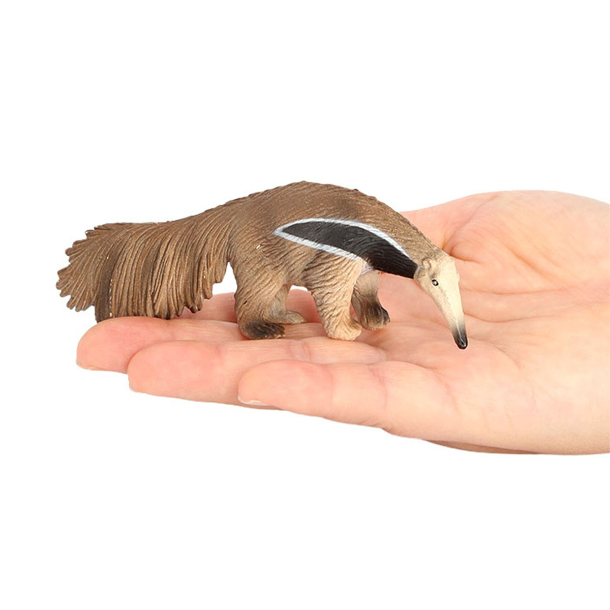 Ein braunes Ameisenbär-Spielzeug wird in einer Hand vor weißem Hintergrund gehalten.